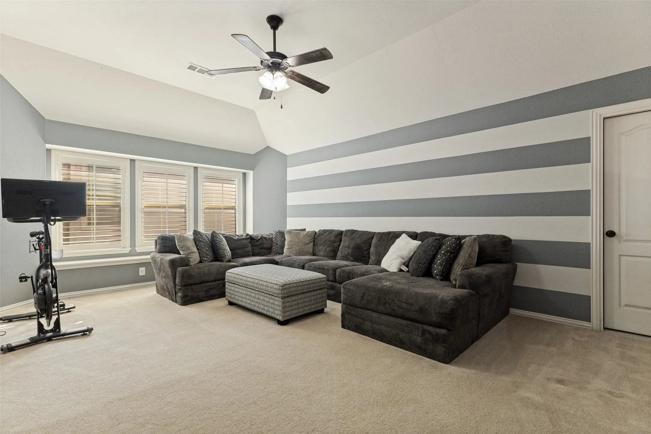 Bonus room with ceiling fan and large windows.