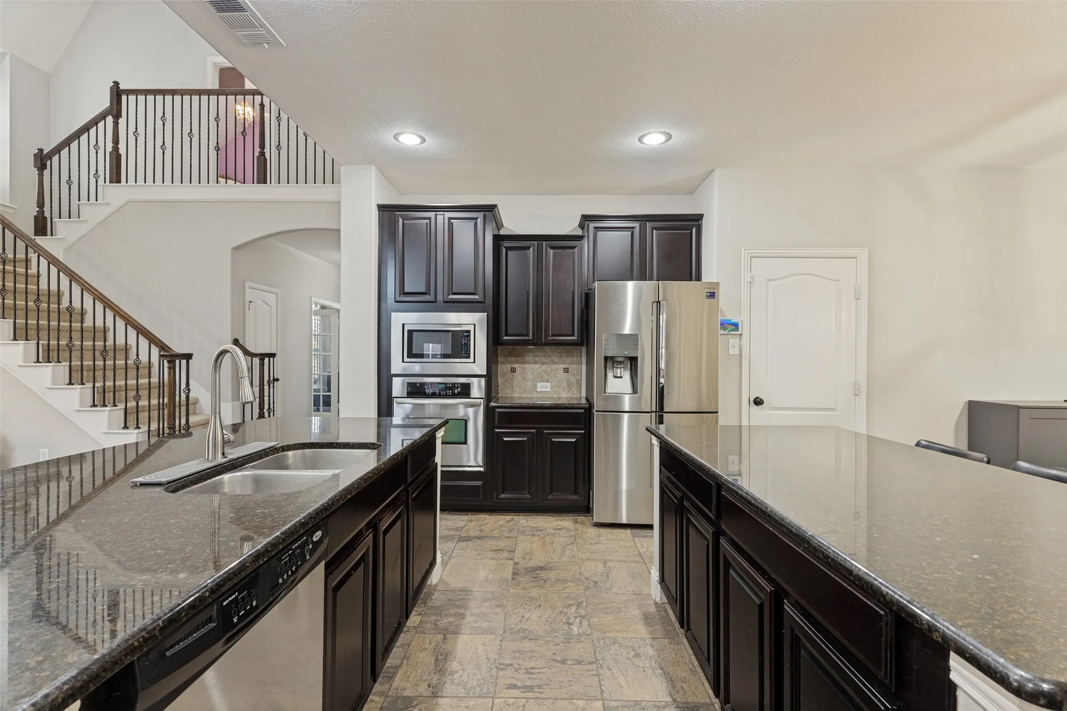 Kitchen with view of both islands, stacked oven and microwwave and plenty of cabinet space.