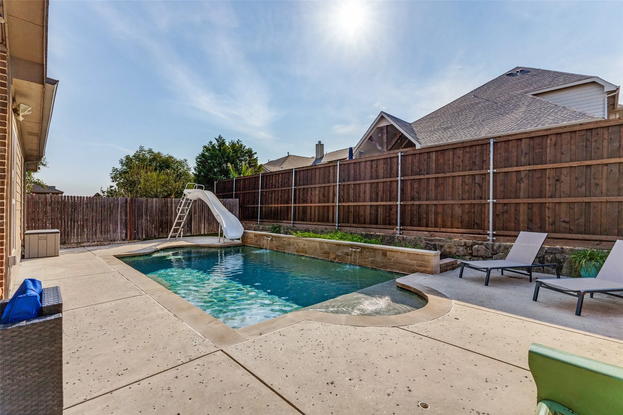 In ground pool with slide and plenty of patio space.