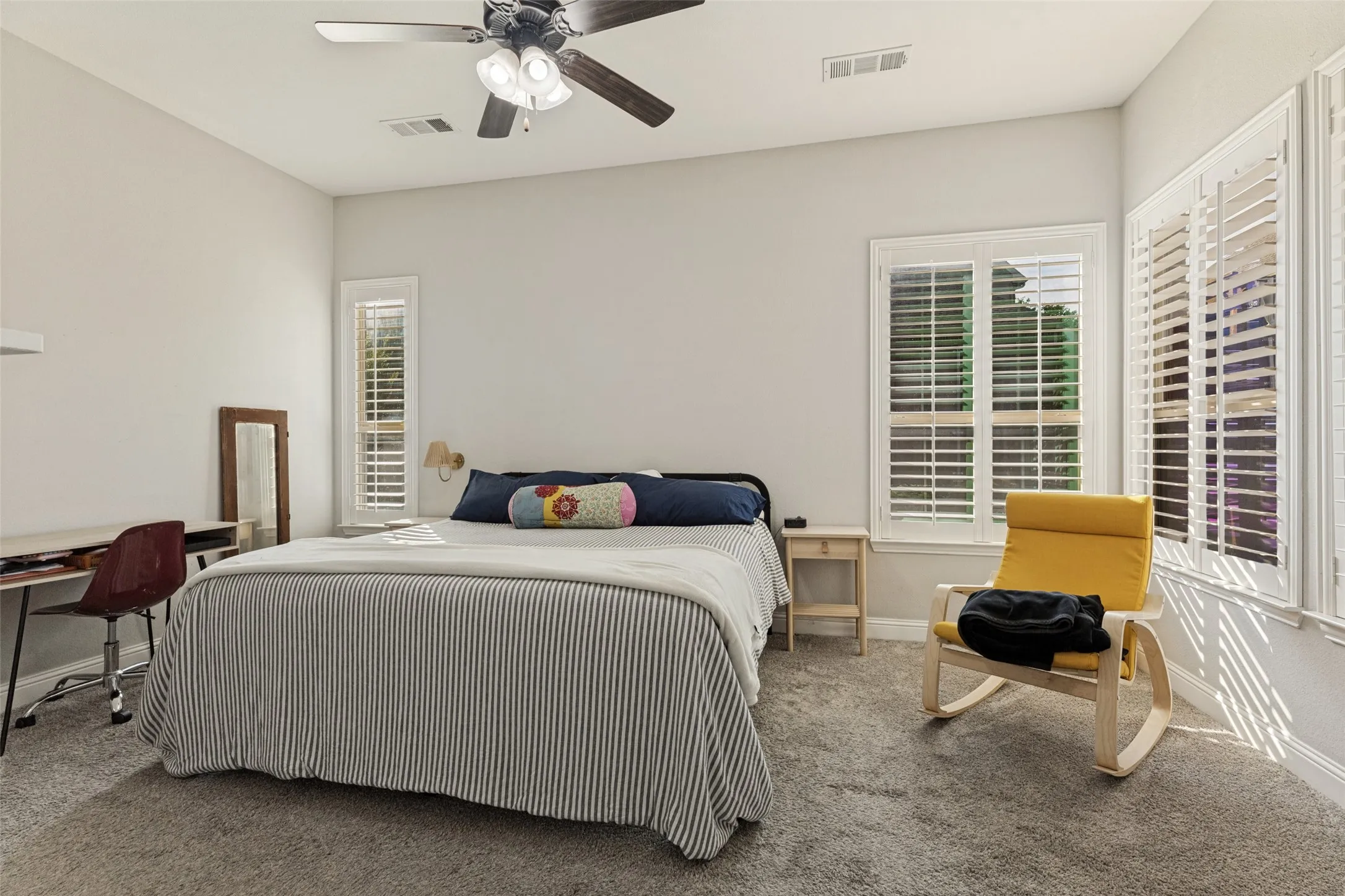 Primary bedroom with ceiling fan and large windows.