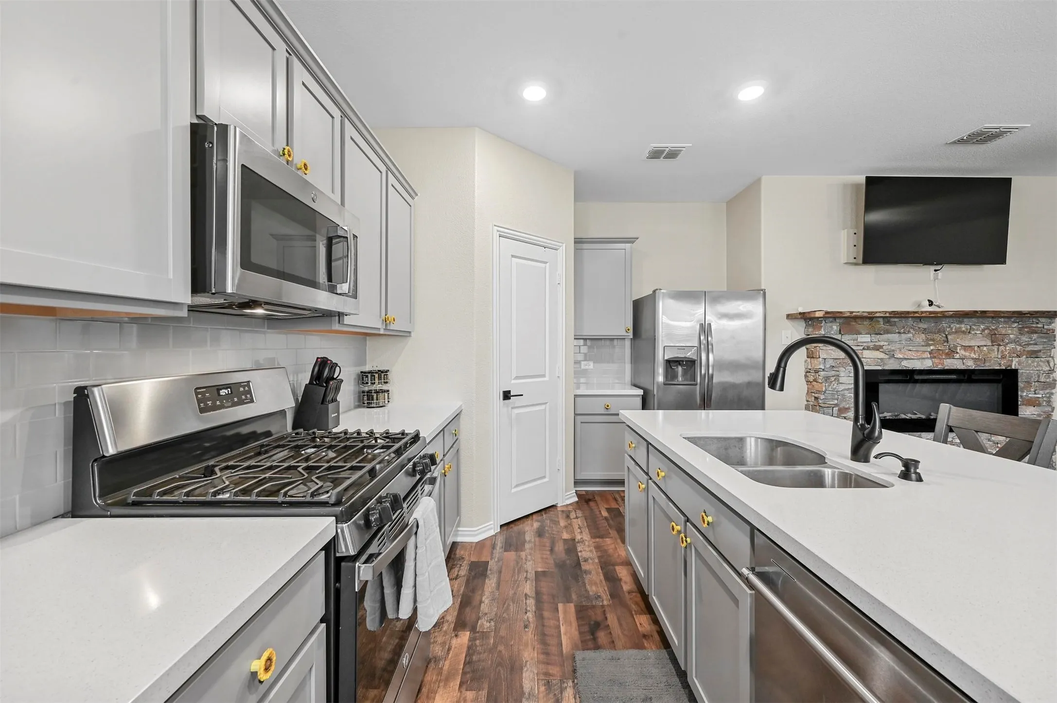 Kitchen featuring dark hardwood / wood-style flooring, sink, gray cabinetry, and stainless steel appliances
