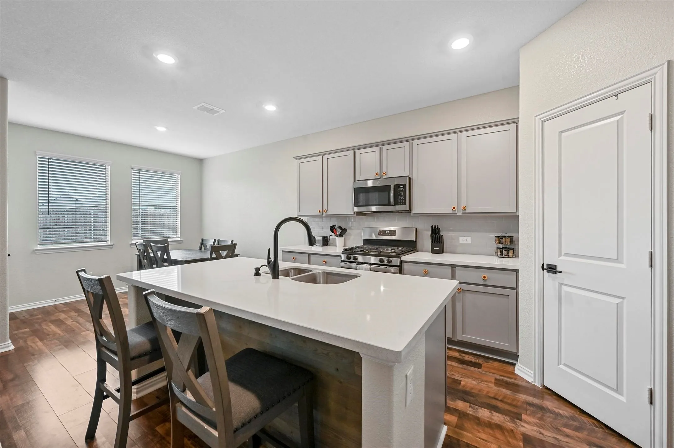 Kitchen with gray cabinetry, a center island with sink, sink, and appliances with stainless steel finishes