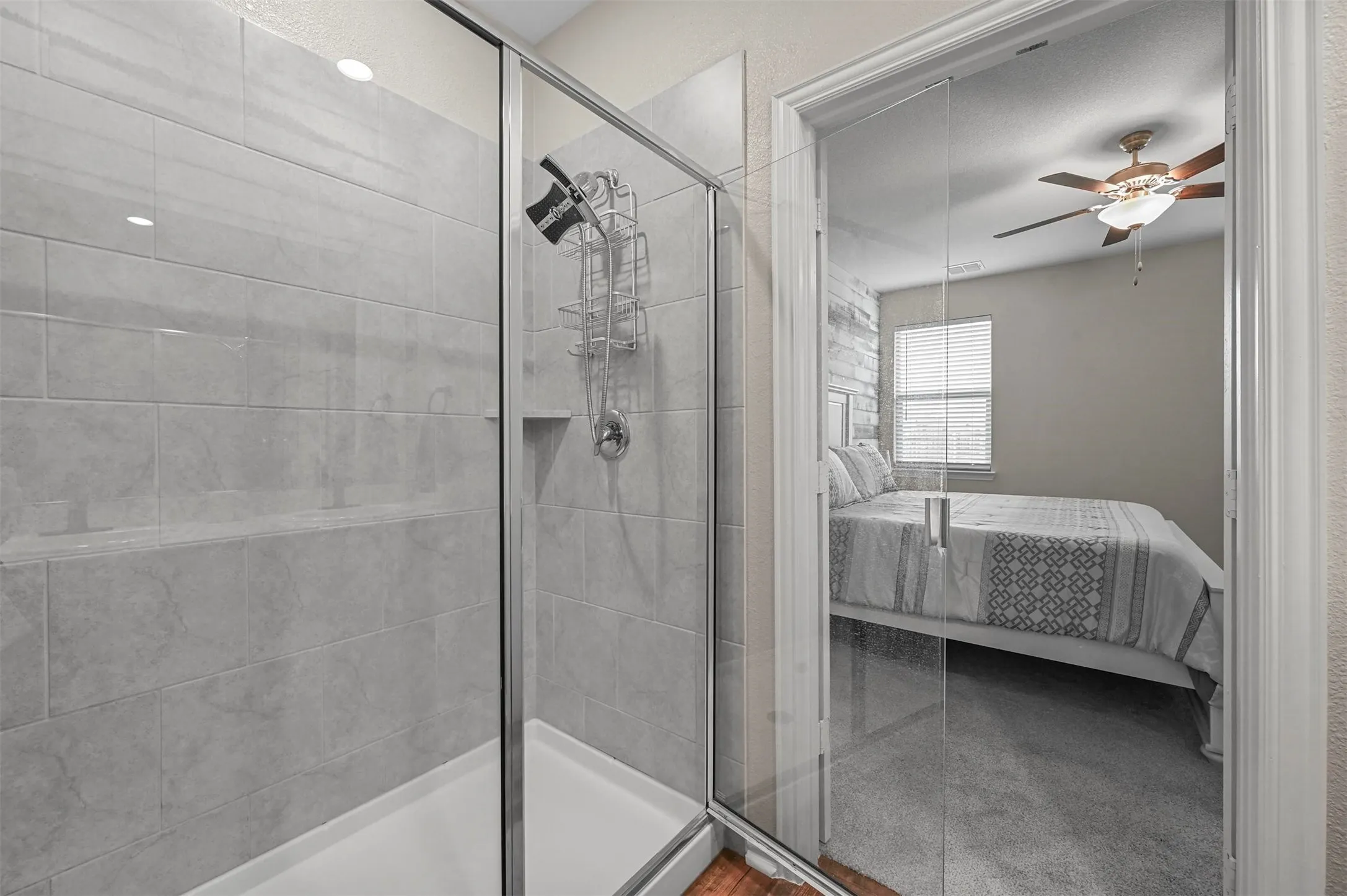 Bathroom featuring ceiling fan and a shower with shower door