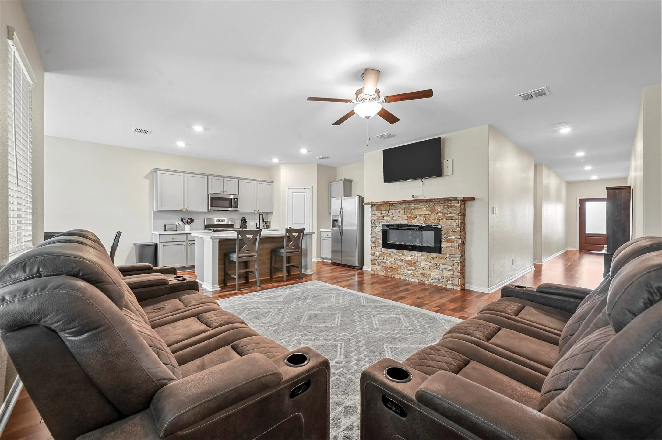 Living room featuring hardwood / wood-style floors, ceiling fan, and a fireplace