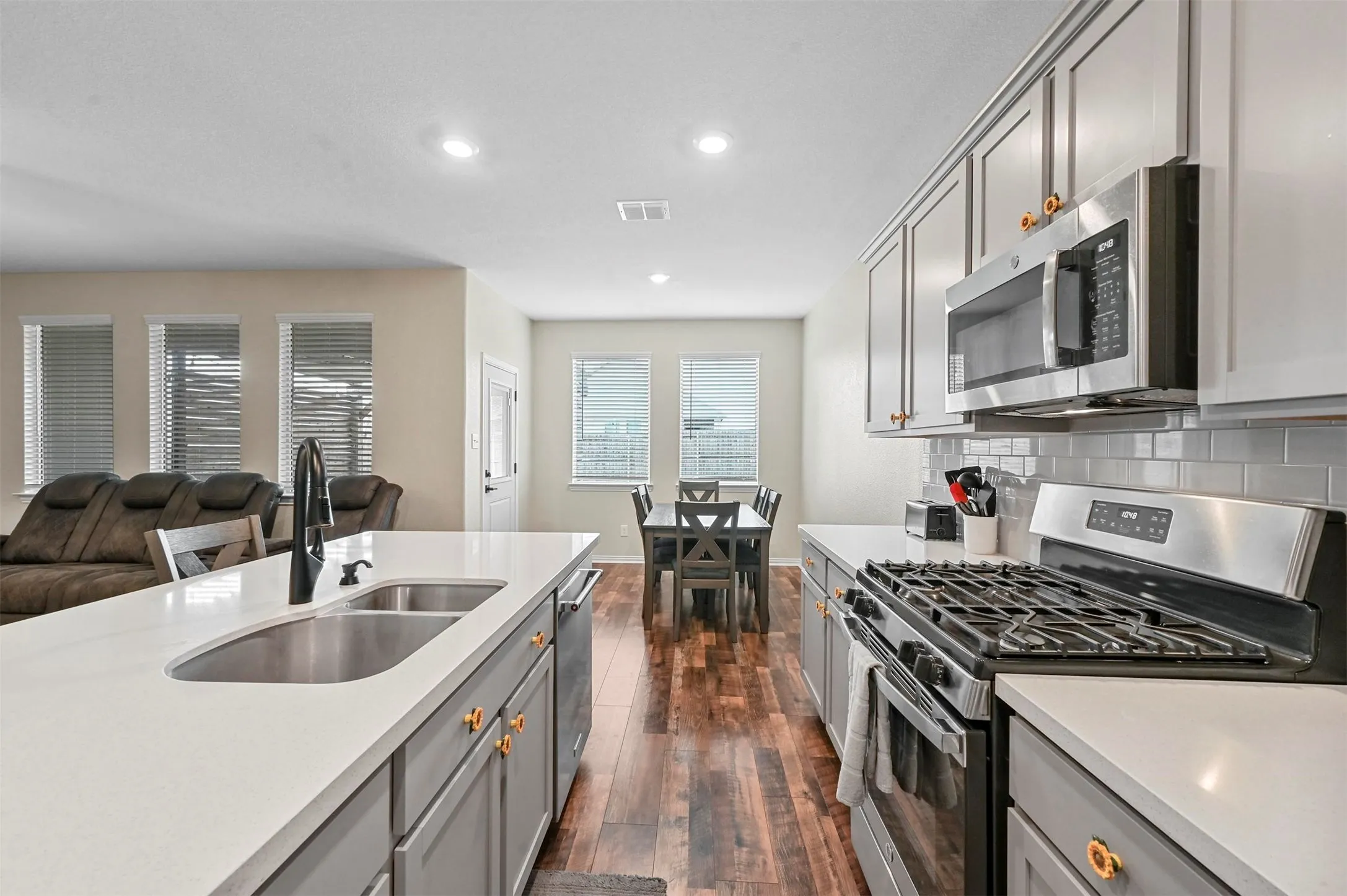 Kitchen featuring gray cabinetry, sink, decorative backsplash, dark hardwood / wood-style flooring, and stainless steel appliances