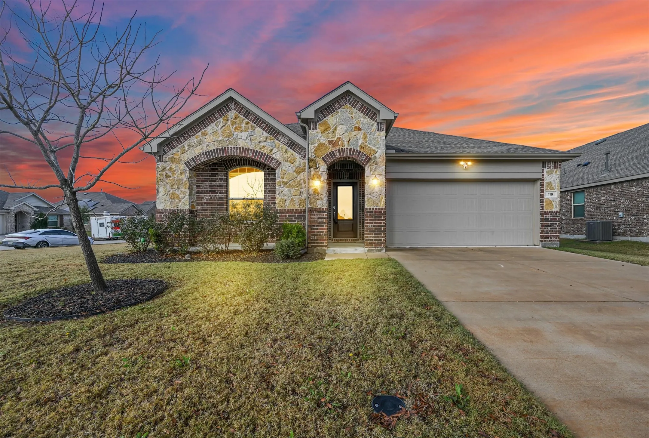 View of front of property featuring a yard, cooling unit, and a garage