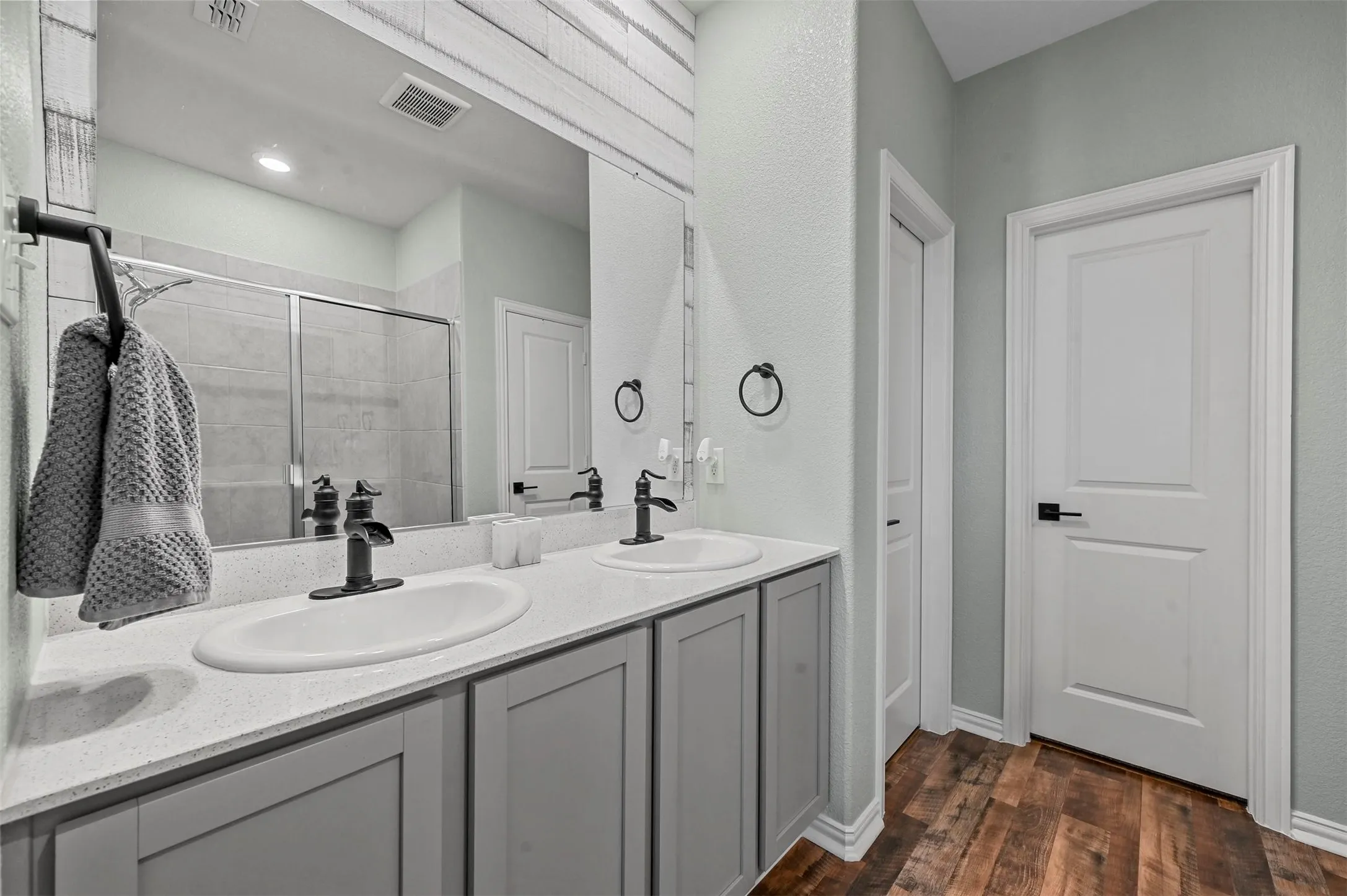 Bathroom featuring hardwood / wood-style flooring, vanity, and a shower with shower door
