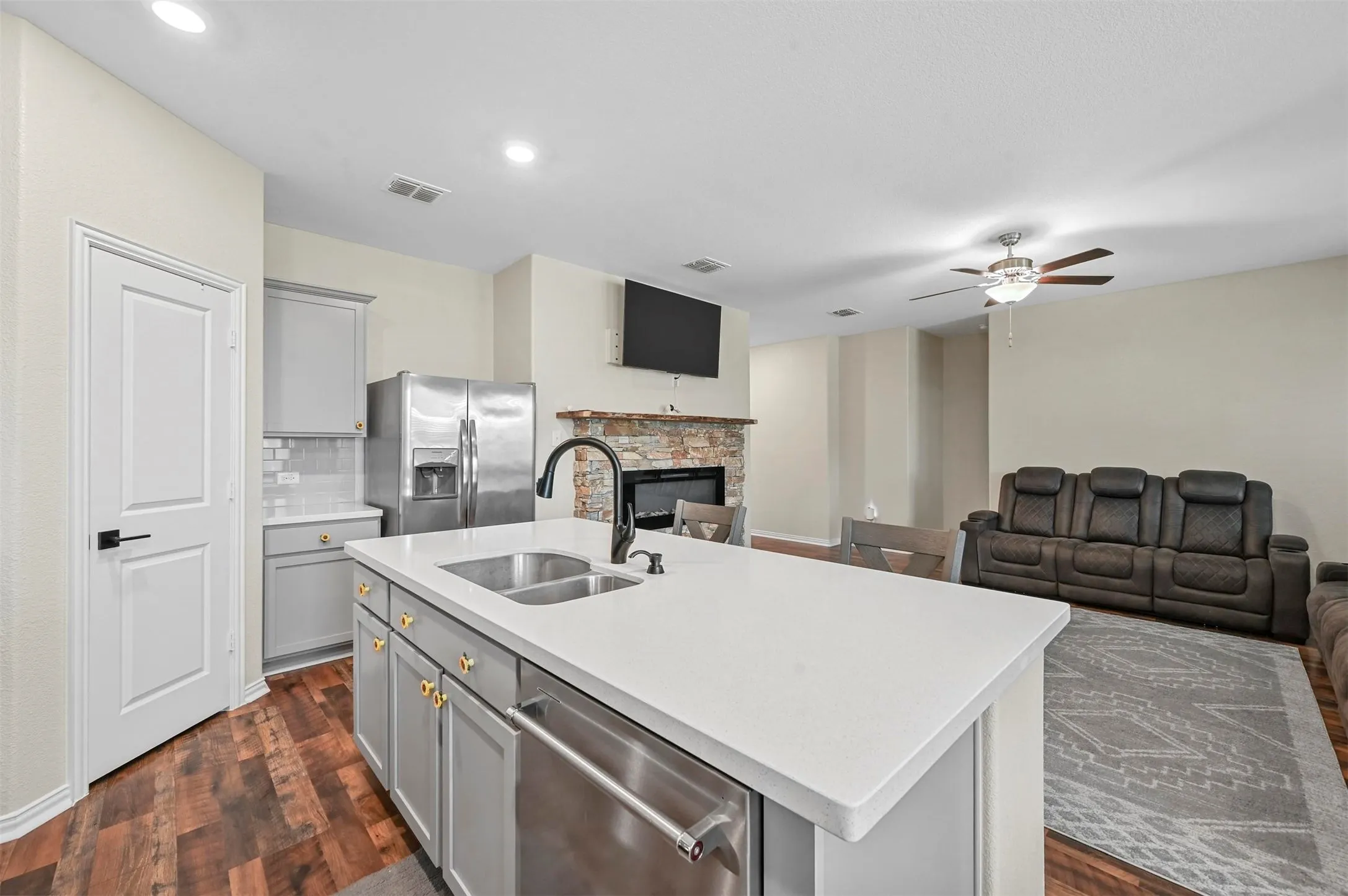 Kitchen featuring sink, decorative backsplash, a fireplace, an island with sink, and stainless steel appliances