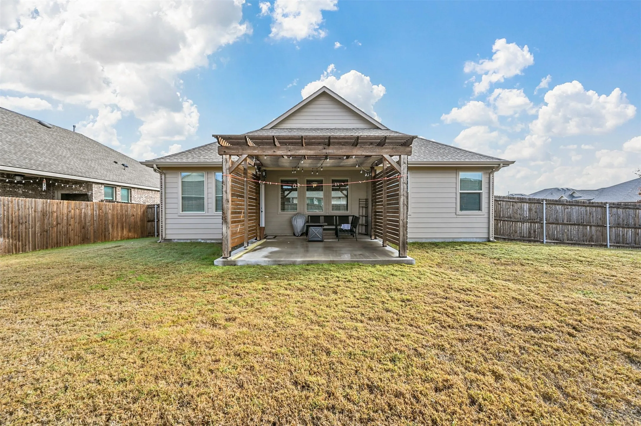 Back of house featuring a pergola, a patio, and a lawn