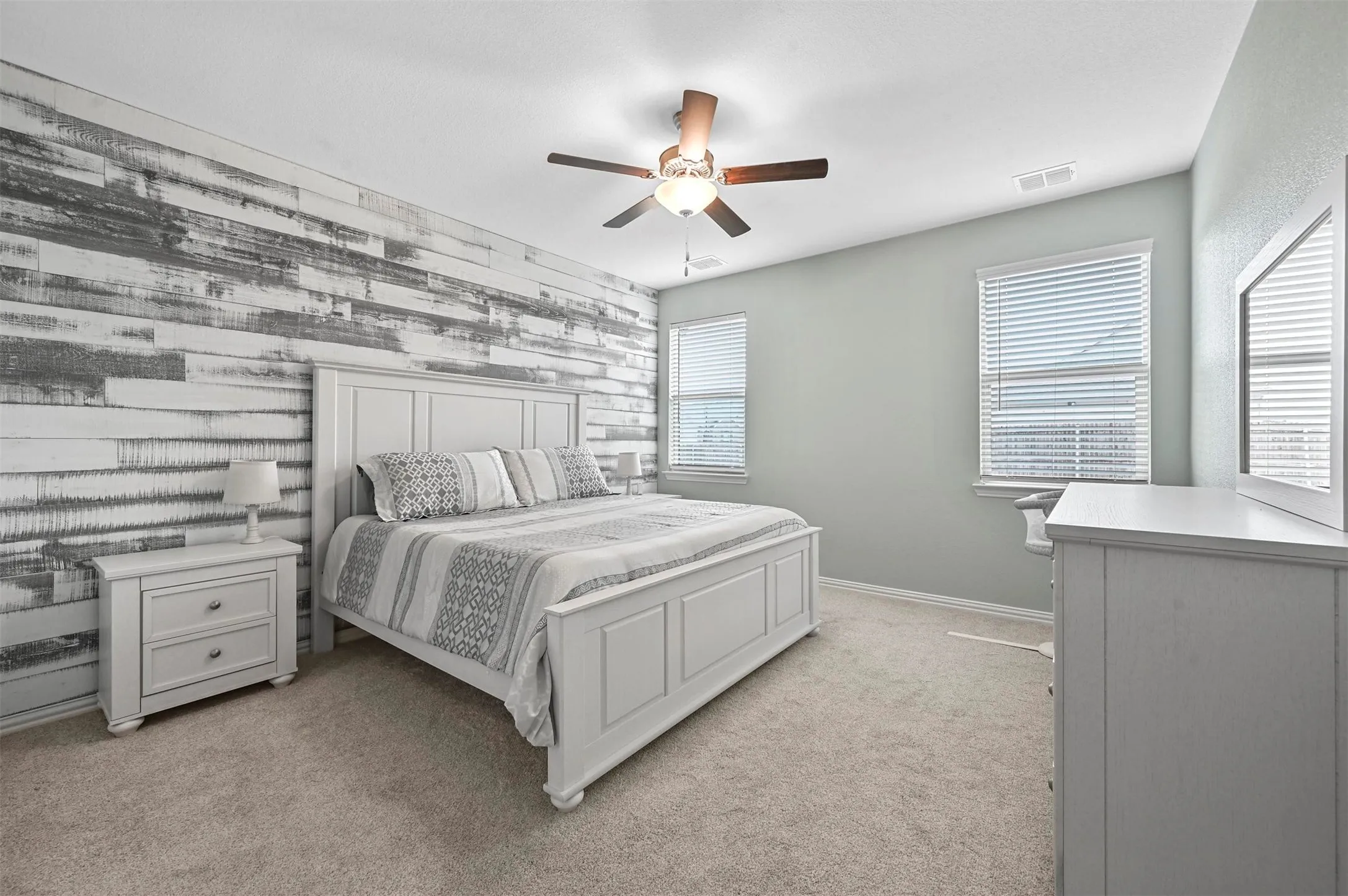 Bedroom featuring ceiling fan, wood walls, and light carpet
