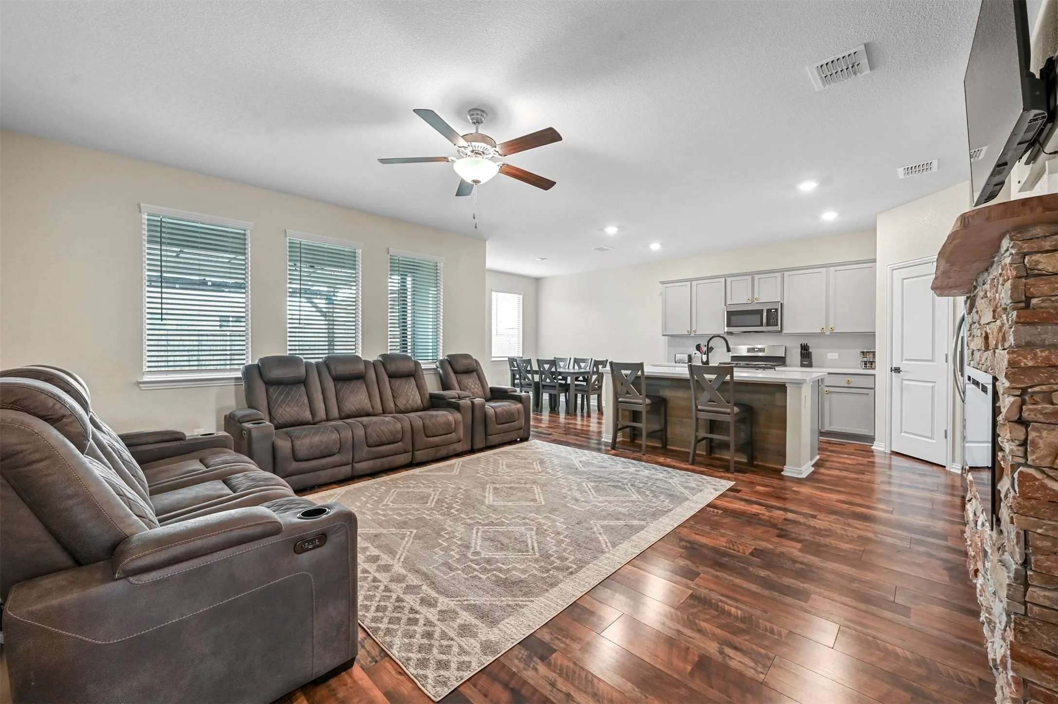 Living room featuring a textured ceiling, ceiling fan, and dark hardwood / wood-style floors