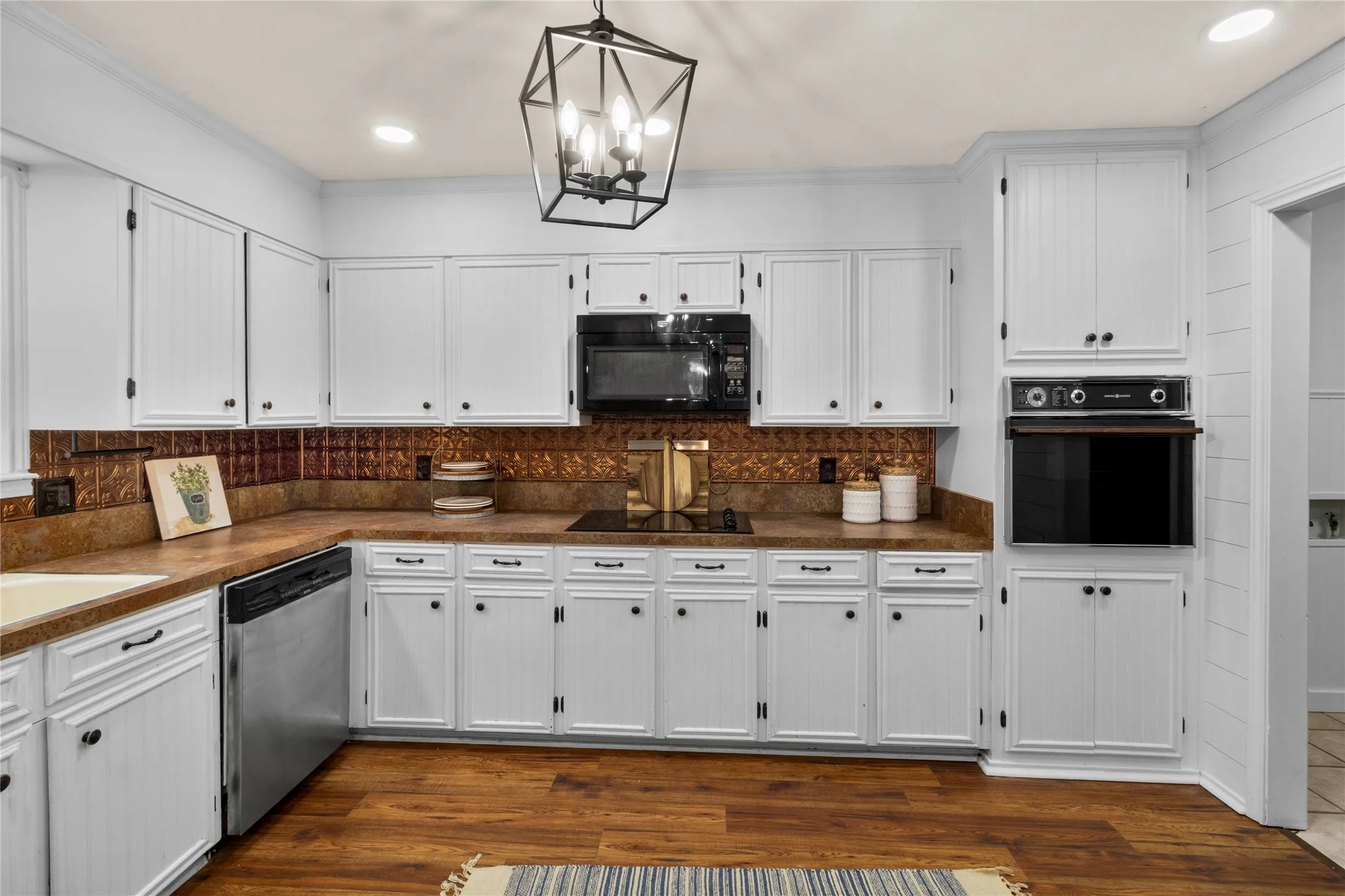 Kitchen featuring white cabinetry, built-in oven, black cooktop, stainless steel dishwasher, and wood-finish flooring