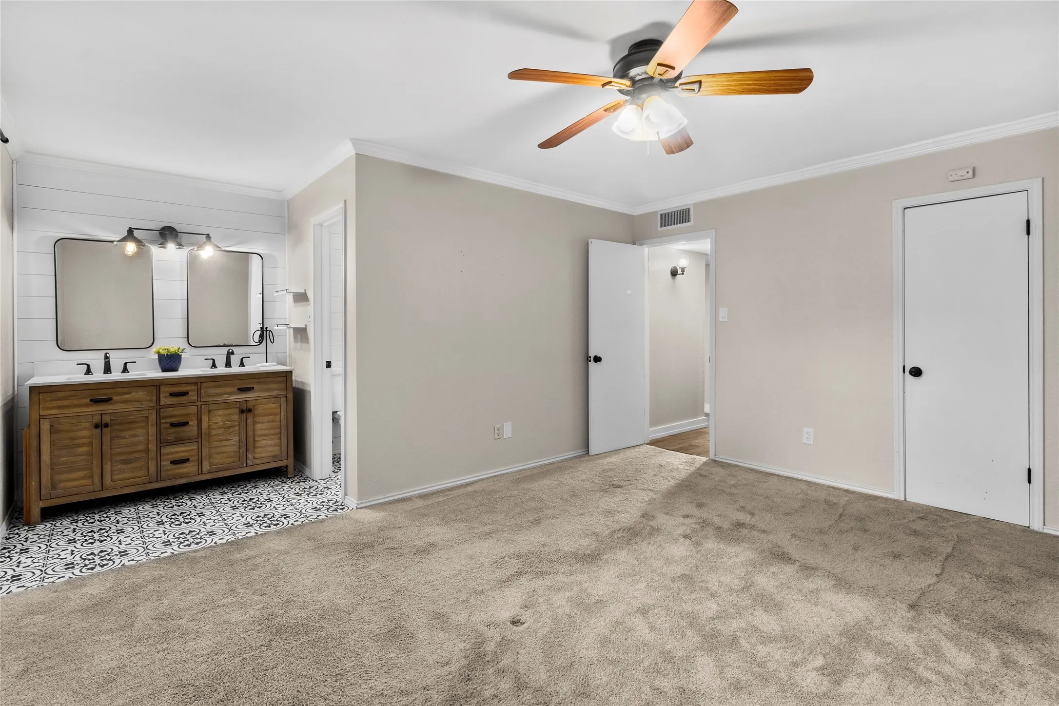 Spacious room featuring neutral carpeting, a ceiling fan, and crown molding