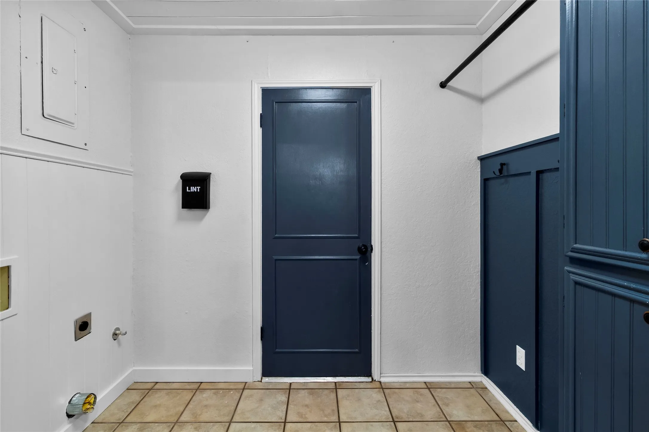 Utility space featuring tiled flooring and a wall-mounted hanging rod