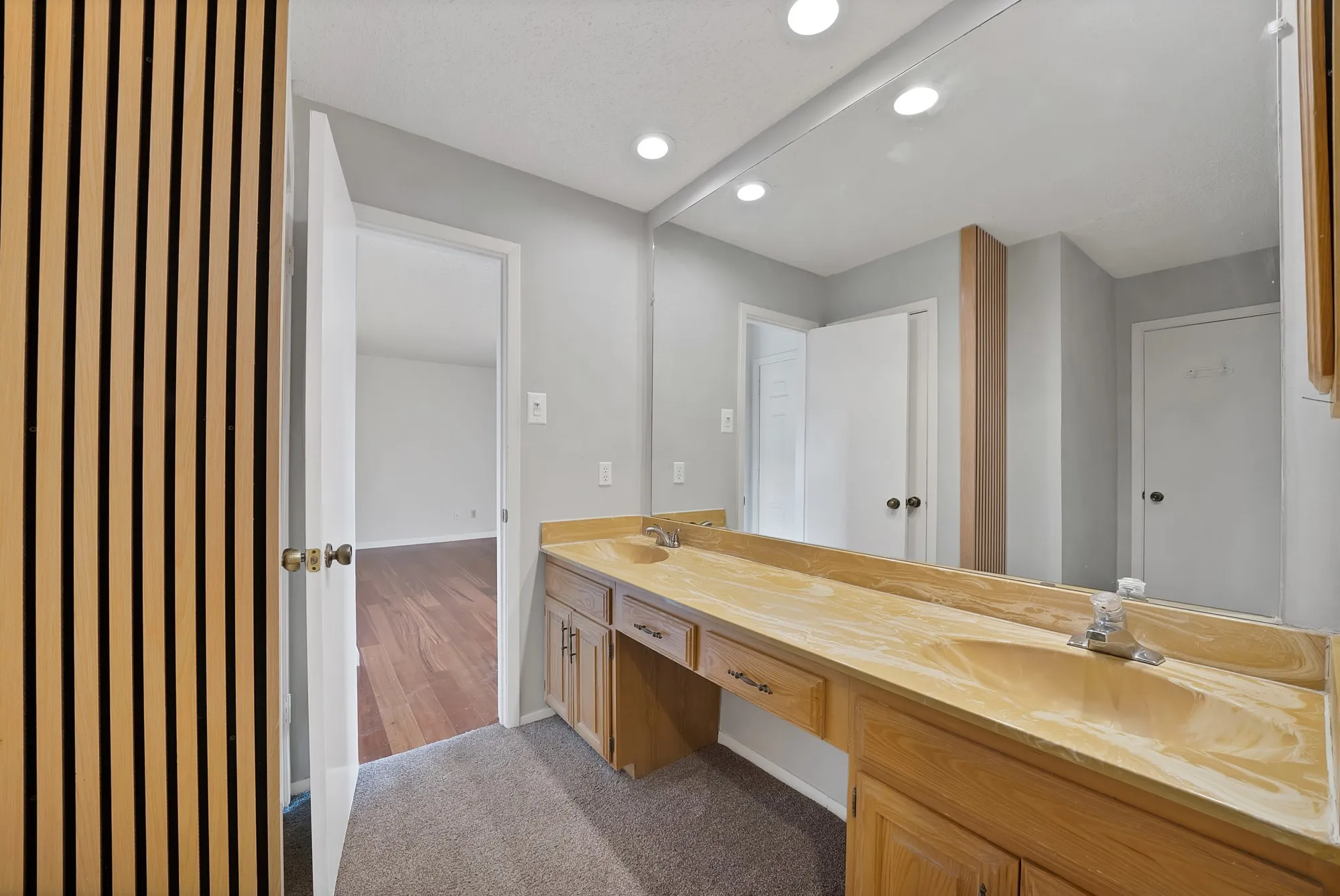 Double vanity with dual basins, recessed lighting, and a large mirror