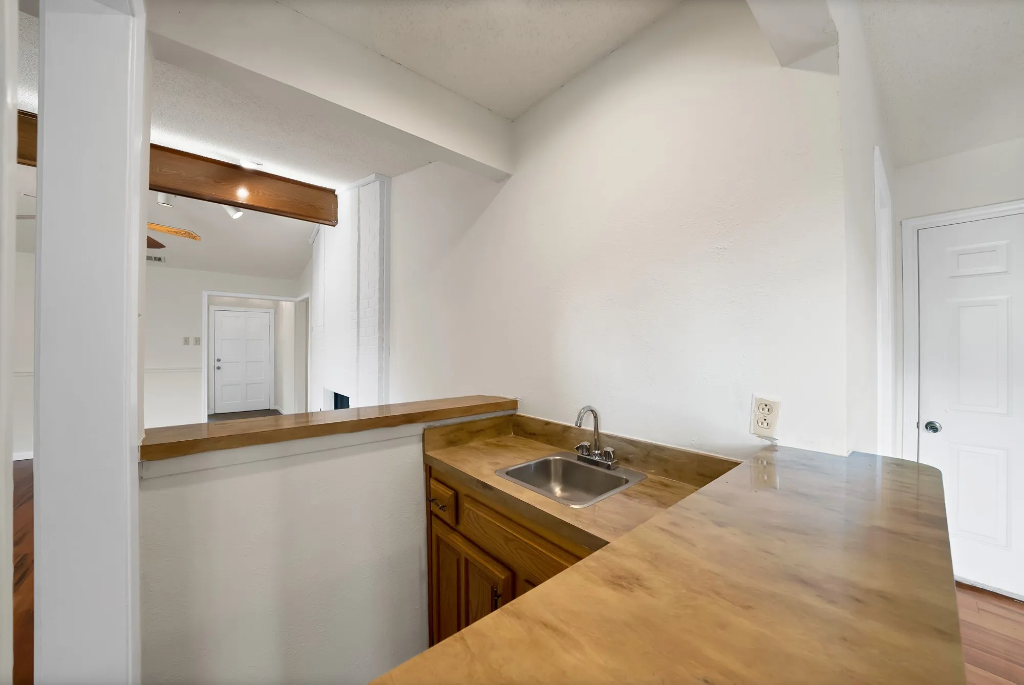 Built-in wet bar featuring a stainless steel sink, wood-finish countertops, and wood cabinetry