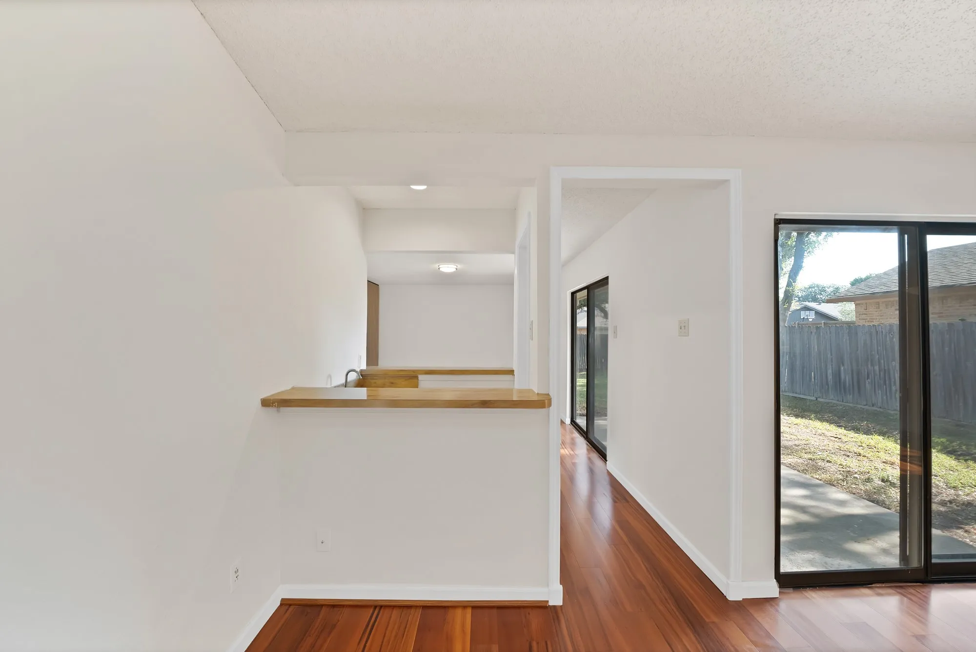 Wood-finish flooring, sliding glass doors, white walls, recessed lighting, and a built-in counter