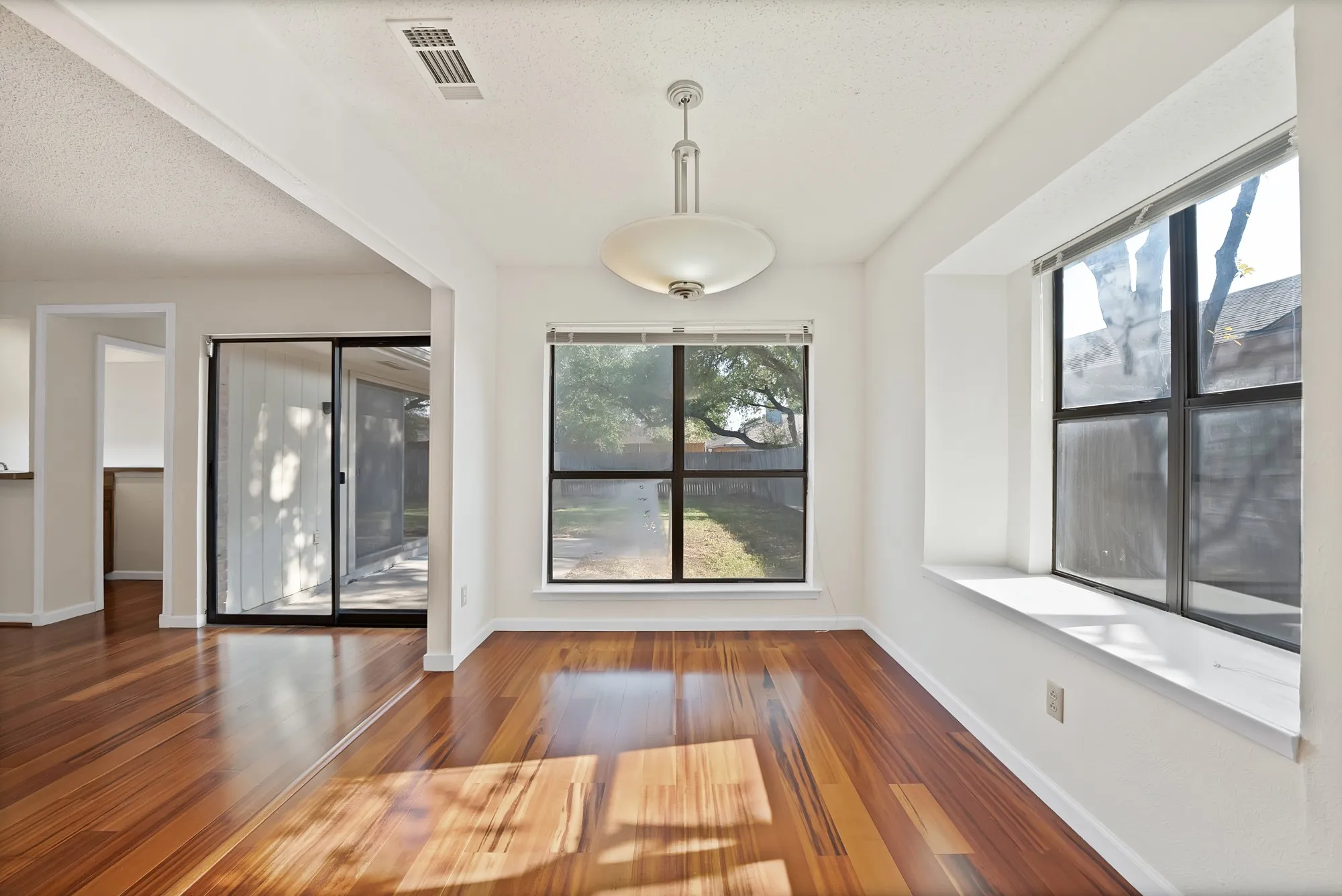 Polished wood-finish flooring, recessed window, and pendant lighting