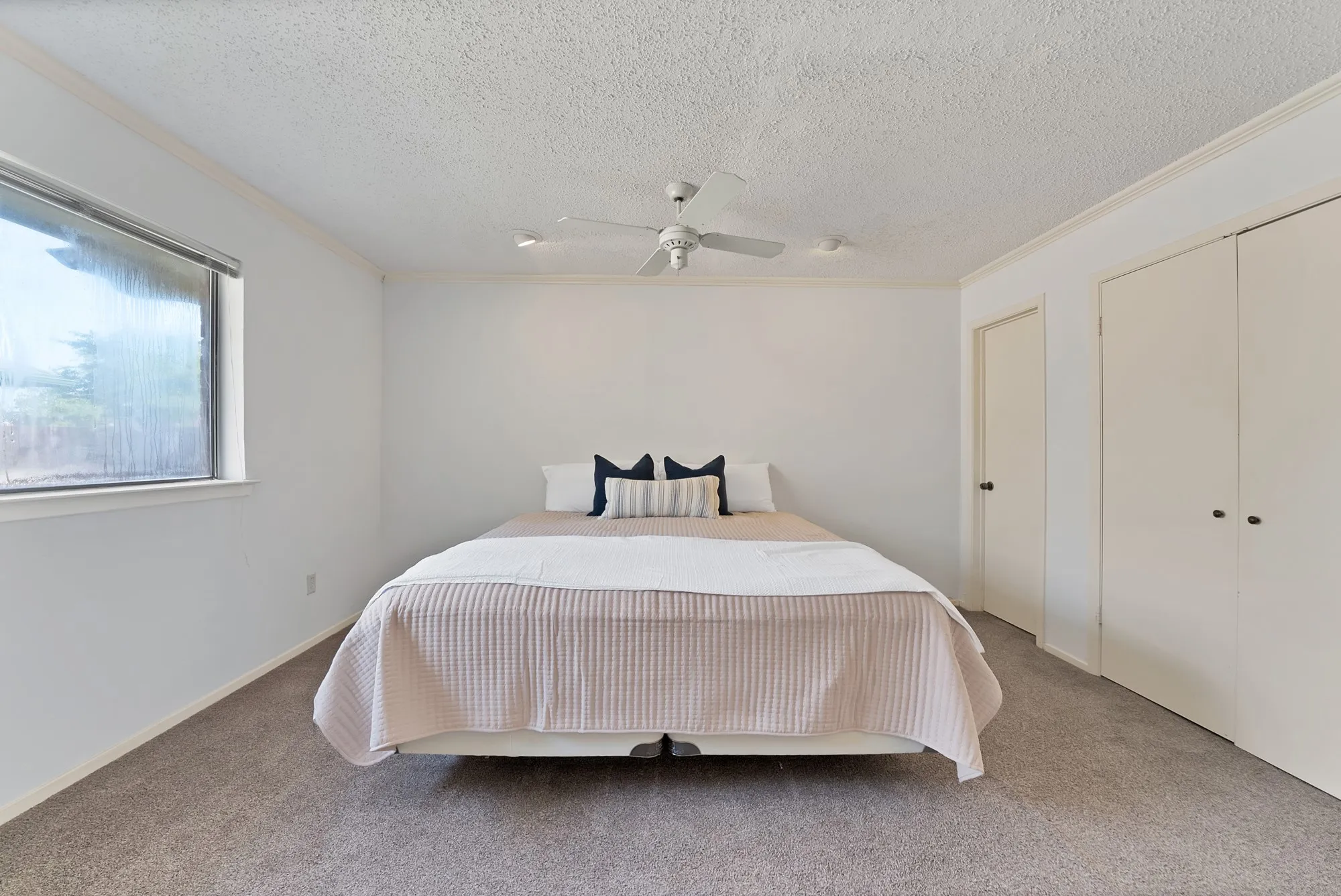Soft gray carpeting, white walls, and a window with a roller shade