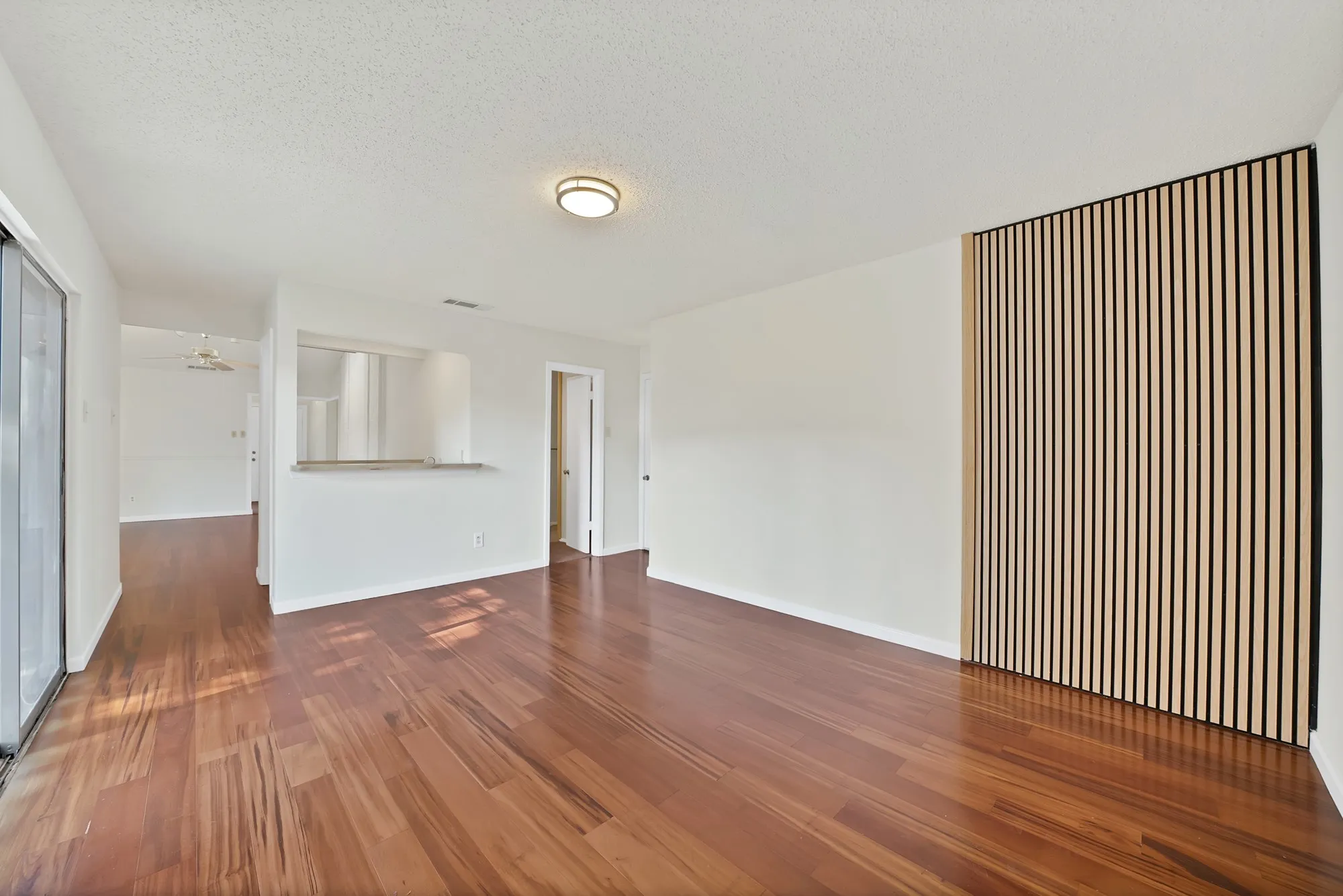 Wood-finish flooring throughout, light wood slat wall paneling, built-in breakfast bar, and a flush mount ceiling light fixture