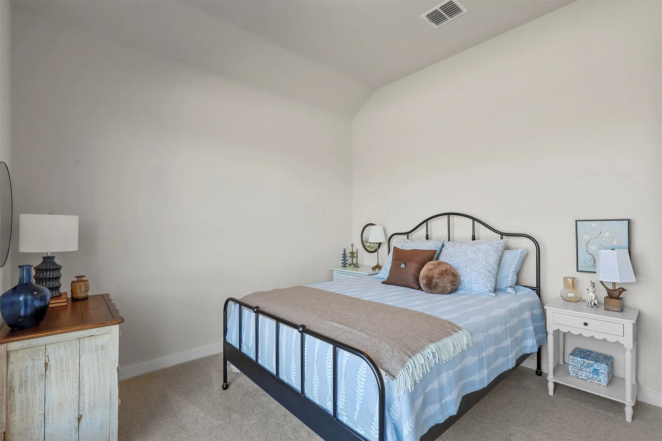 Carpeted bedroom featuring vaulted ceilings and light-colored walls