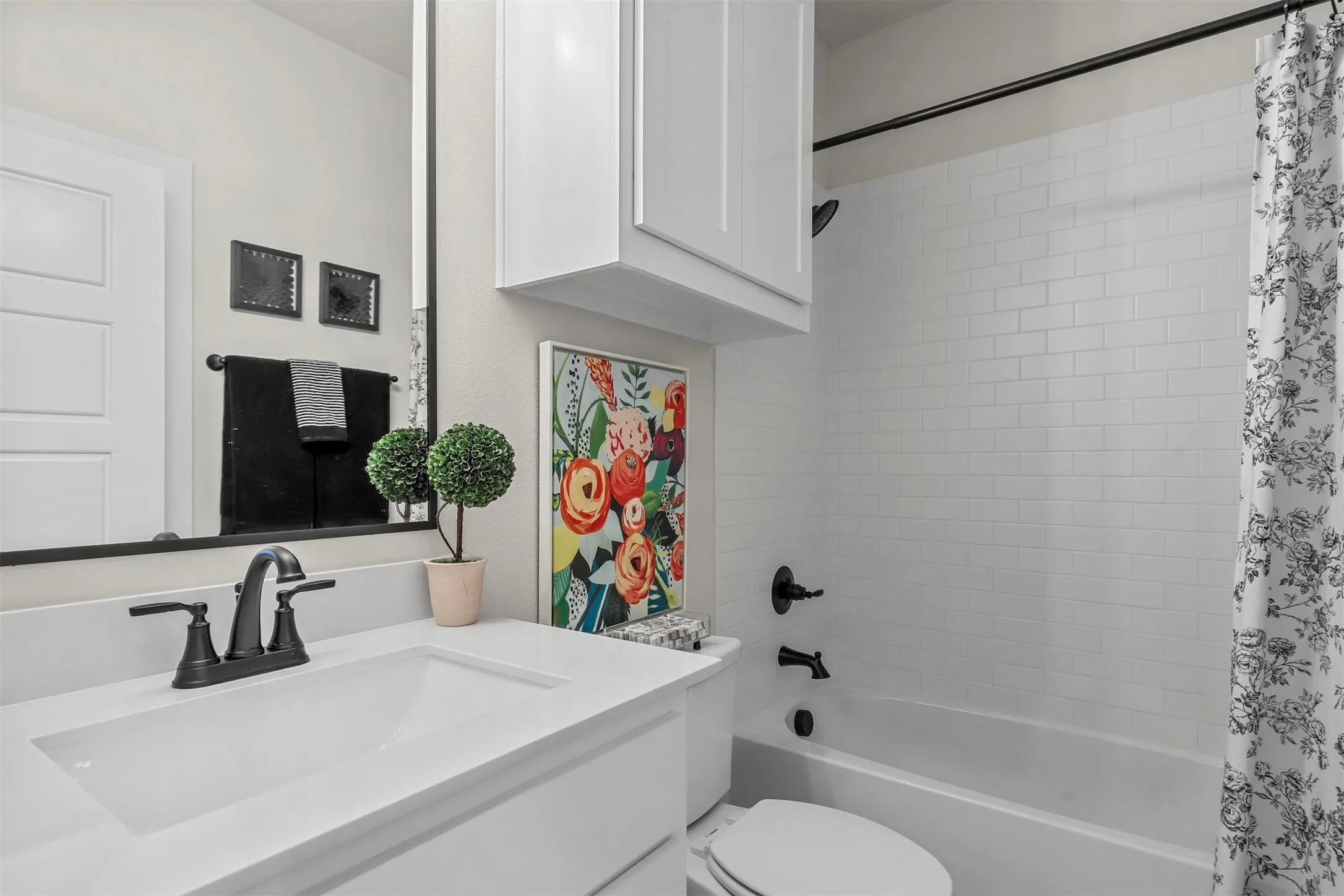 White vanity with integrated sink, matte black faucet, and frameless mirror
