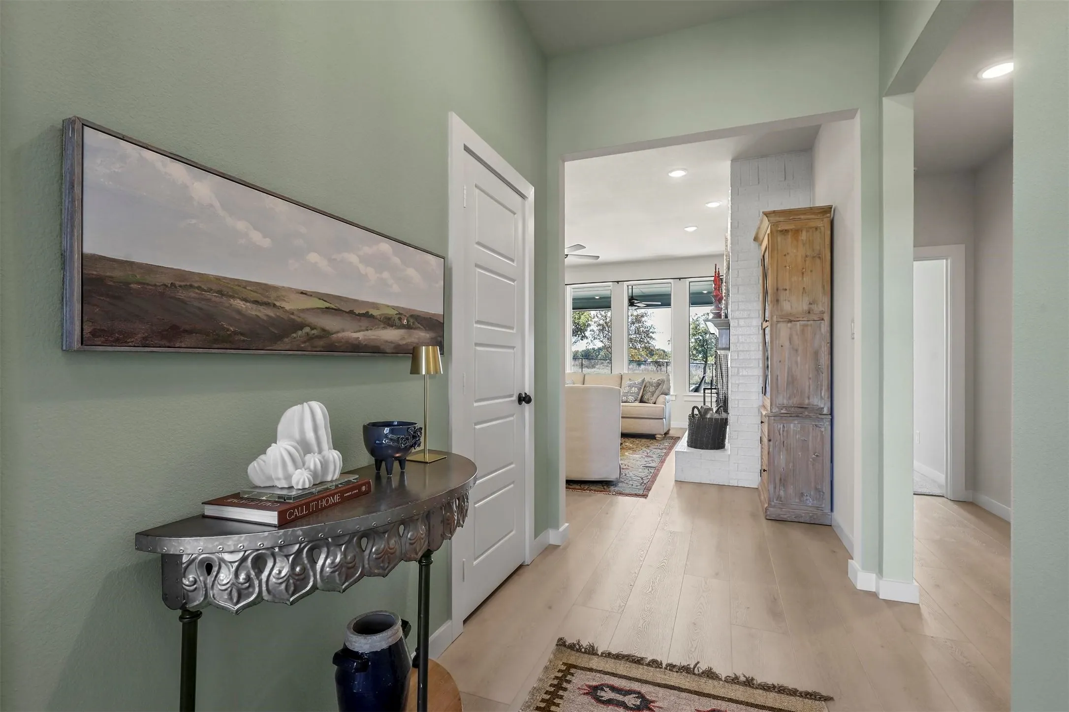 Light wood-finish flooring throughout, framed doorways, recessed lighting, and a white paneled door