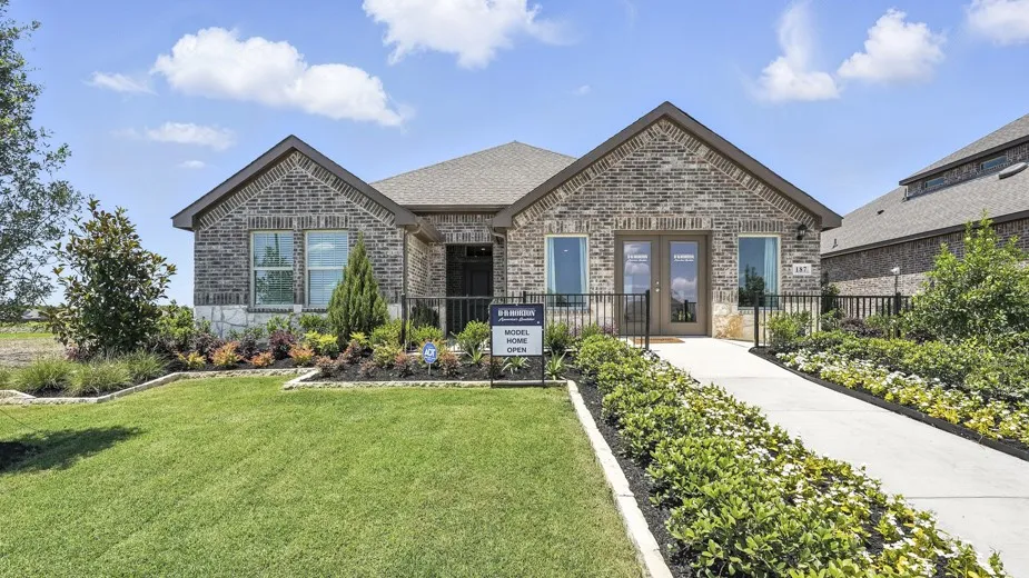 Brick exterior with stone accents, twin gables, a covered entry, and a concrete walkway flanked by mature landscaping