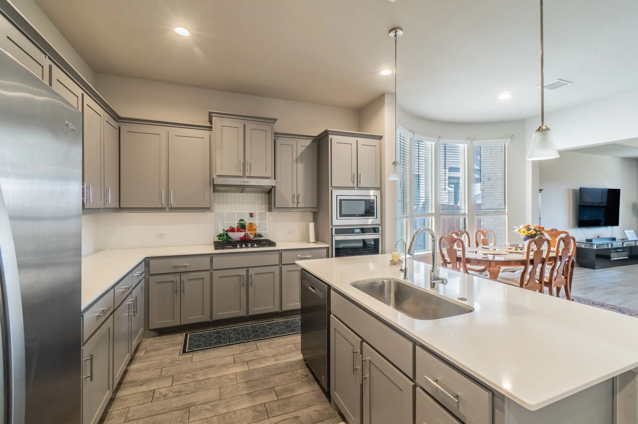 Kitchen featuring light wood-finish flooring, light gray cabinetry with brushed nickel hardware, light countertops, and stainless steel appliances