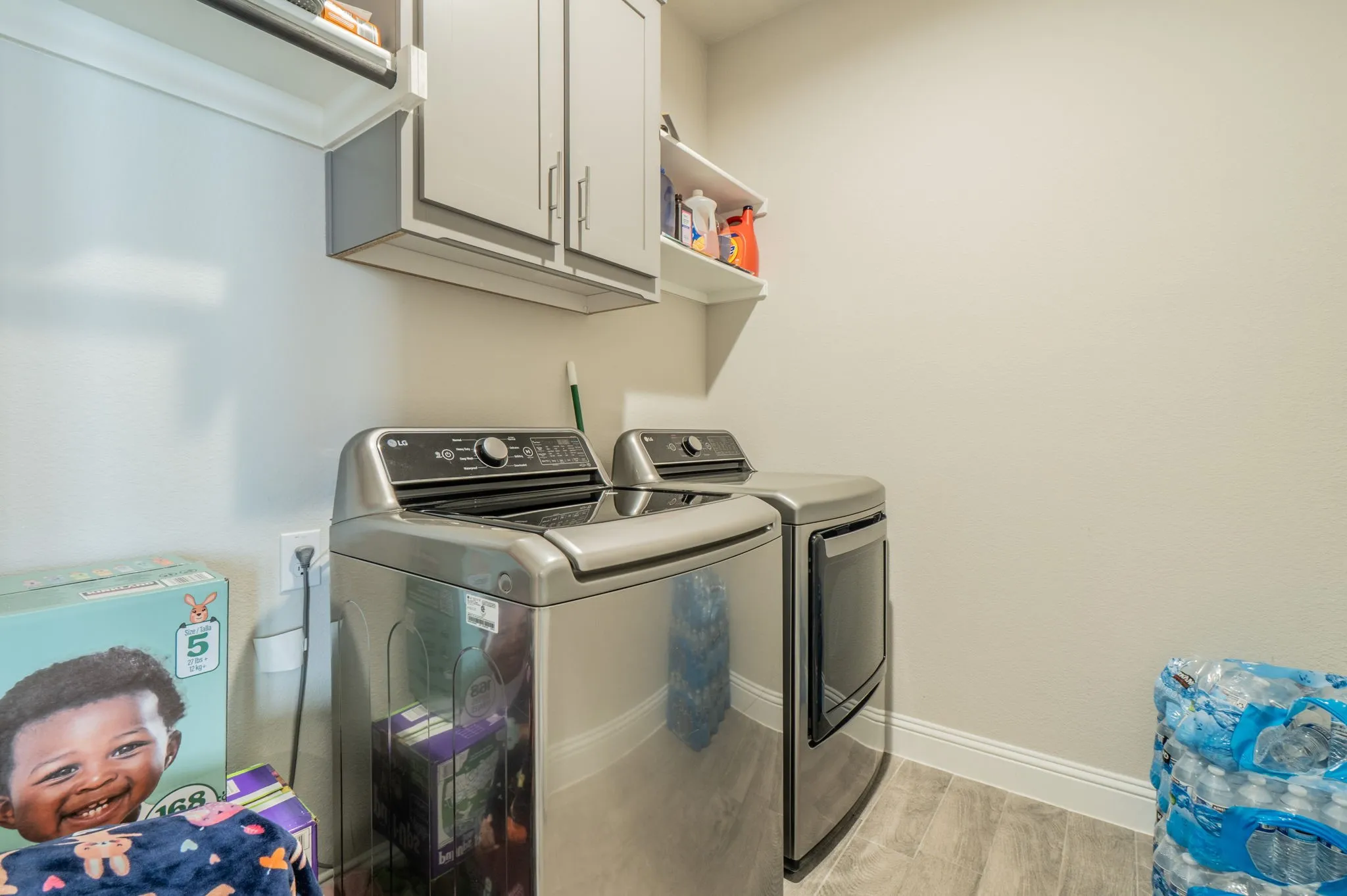 Built-in cabinetry with silver hardware, wall-mounted shelving, wood-finish flooring, and white wall paint