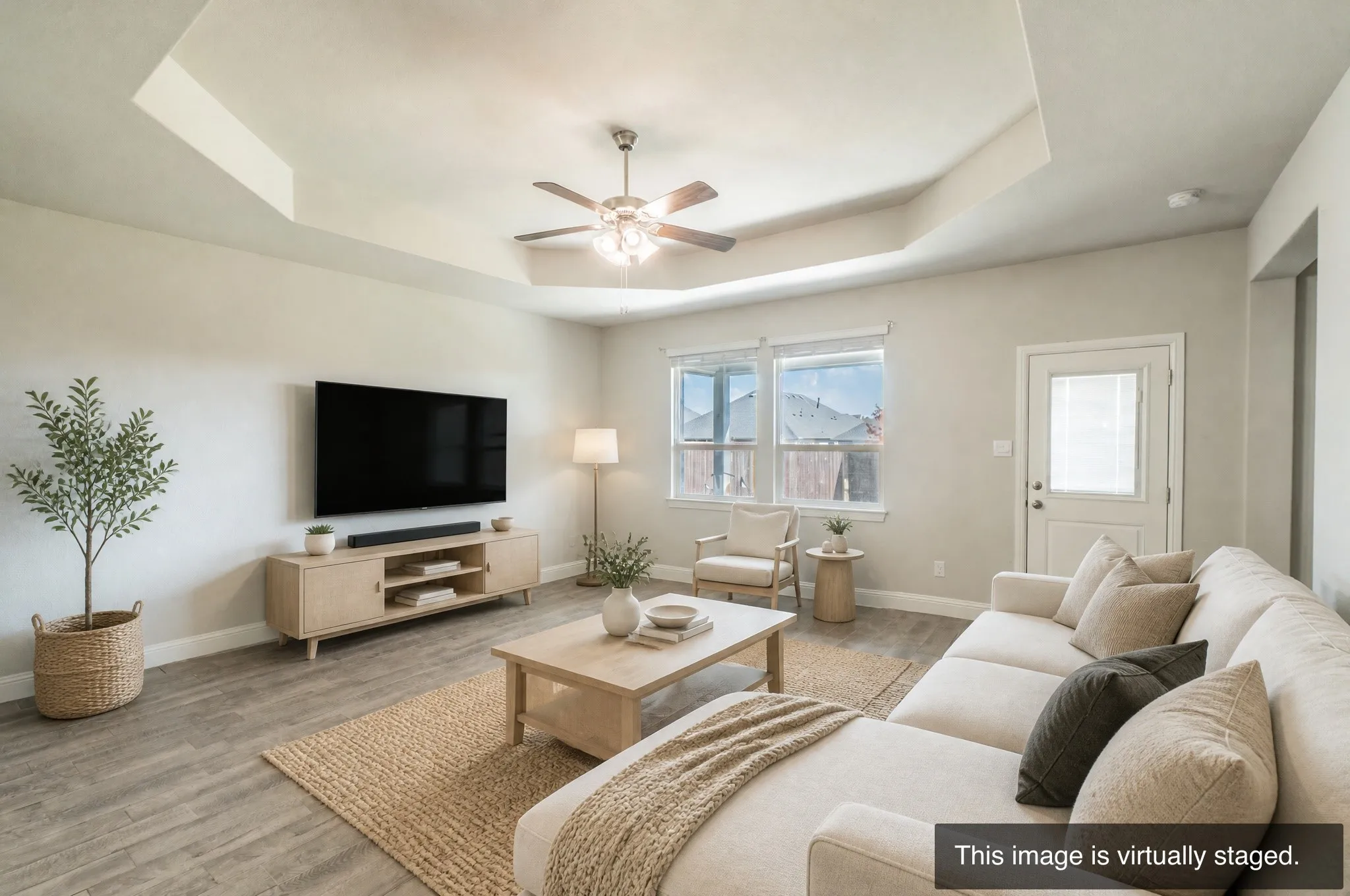Tray ceiling with a ceiling fan, wood-finish flooring, multiple windows, and a rear exterior door