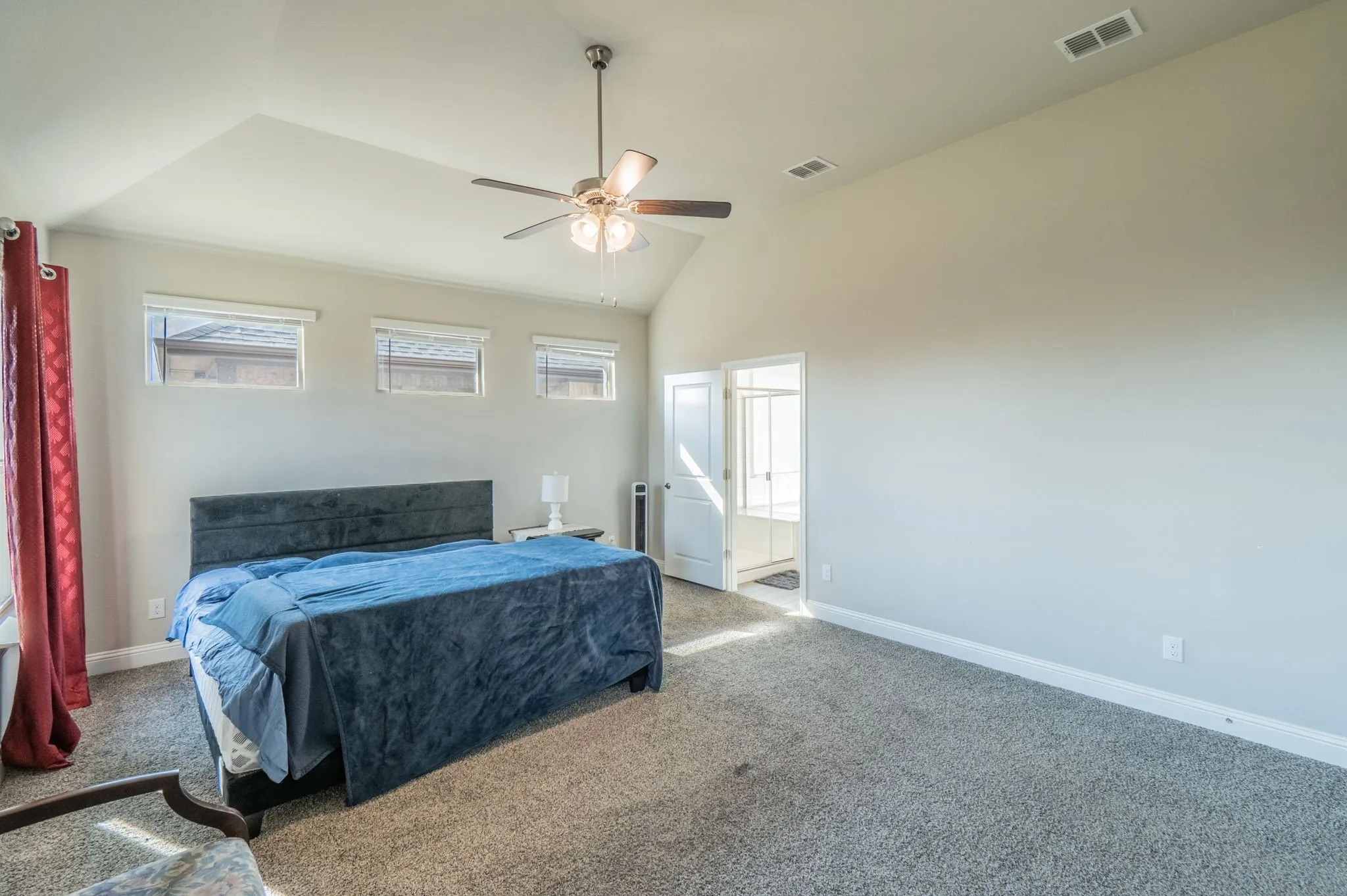Vaulted ceiling, ceiling fan with integrated lighting, three transom windows, and carpeted flooring