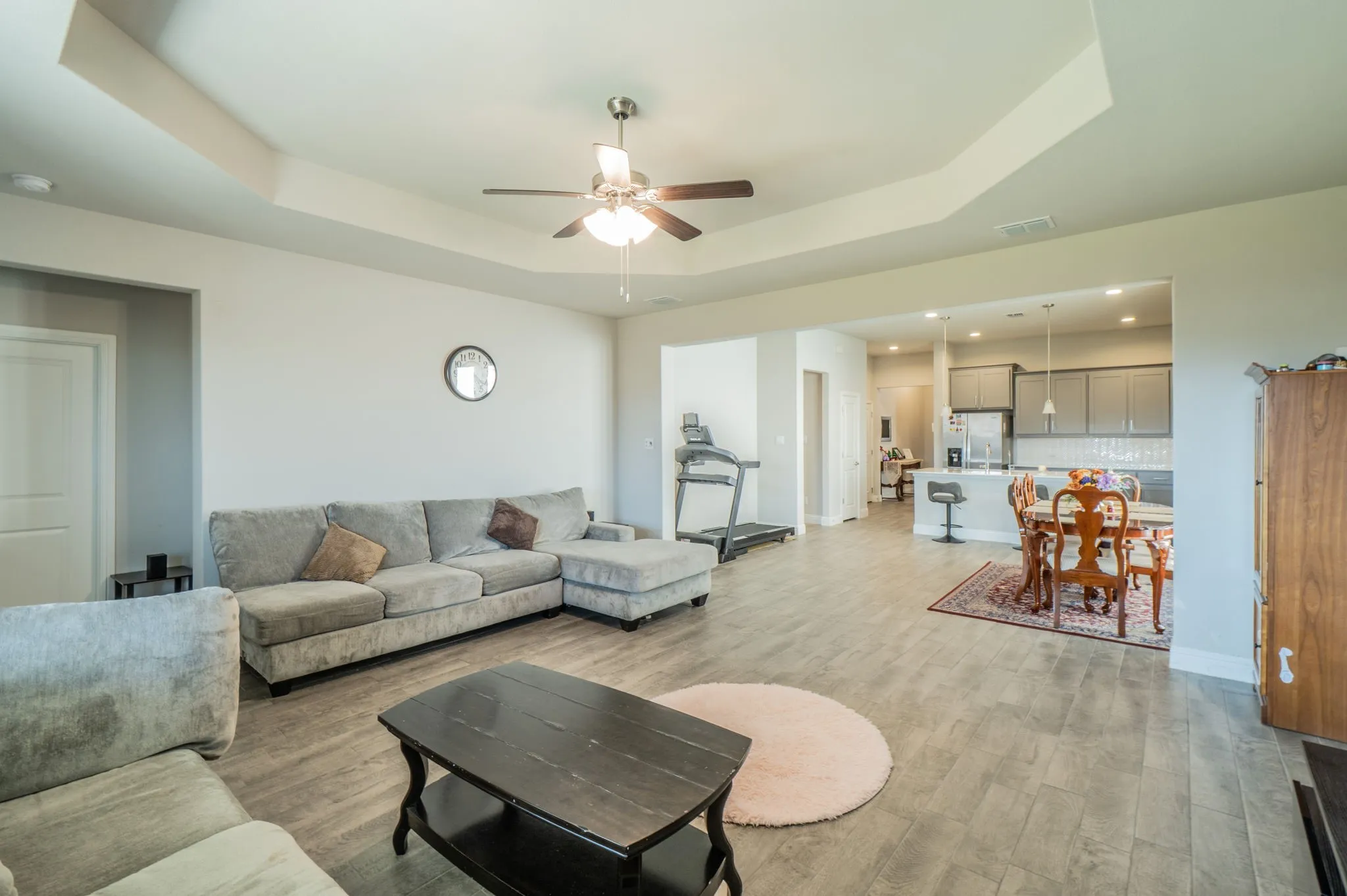Tray ceiling with a ceiling fan, wood-finish flooring, and recessed lighting