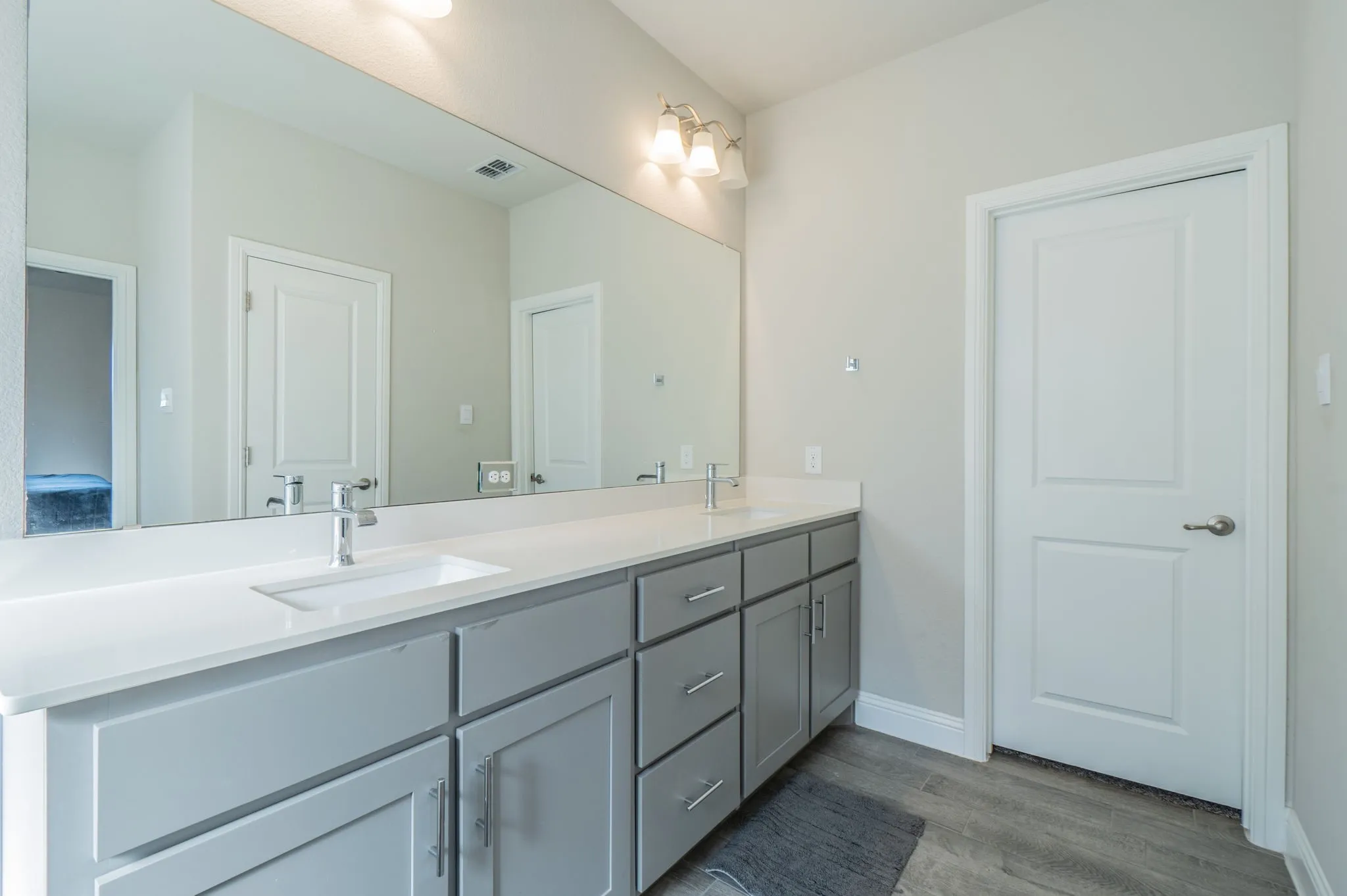 Dual vanity with rectangular undermount sinks, chrome faucets, light grey cabinetry, and white countertops