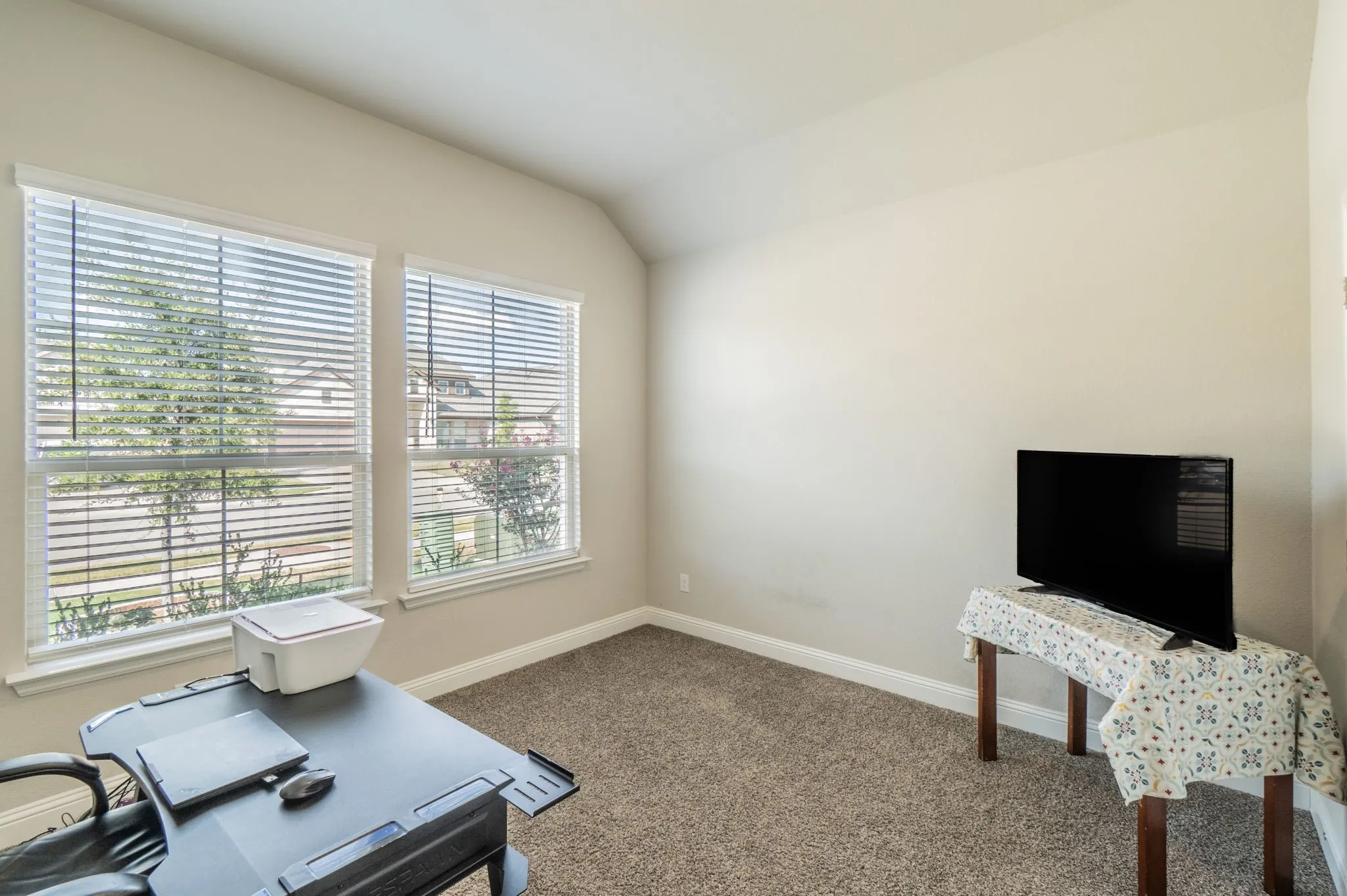 Neutral wall paint, vaulted ceiling, and carpeted flooring