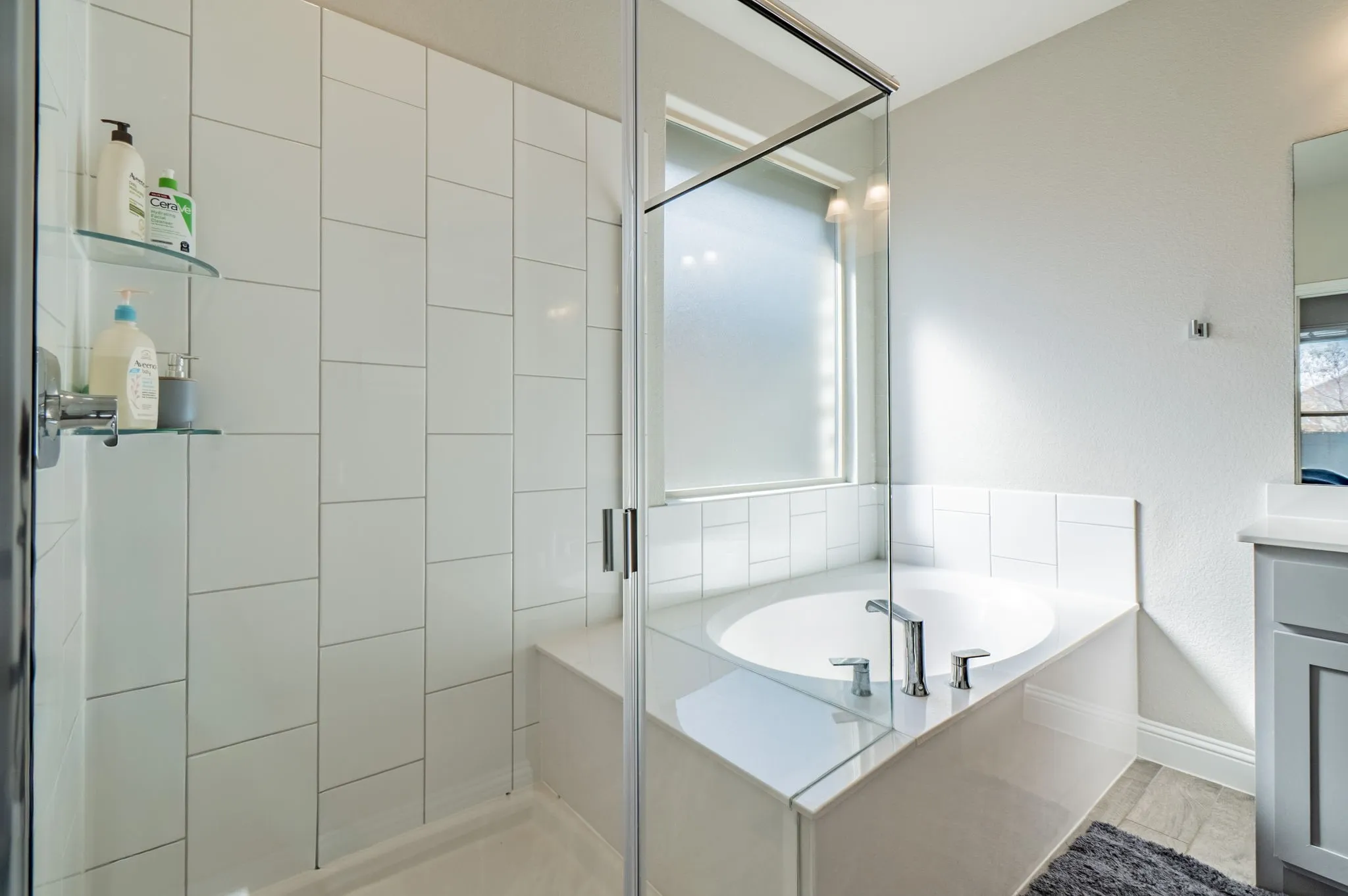 Glass-enclosed shower with white tiled walls, built-in bench, and dual glass shelves