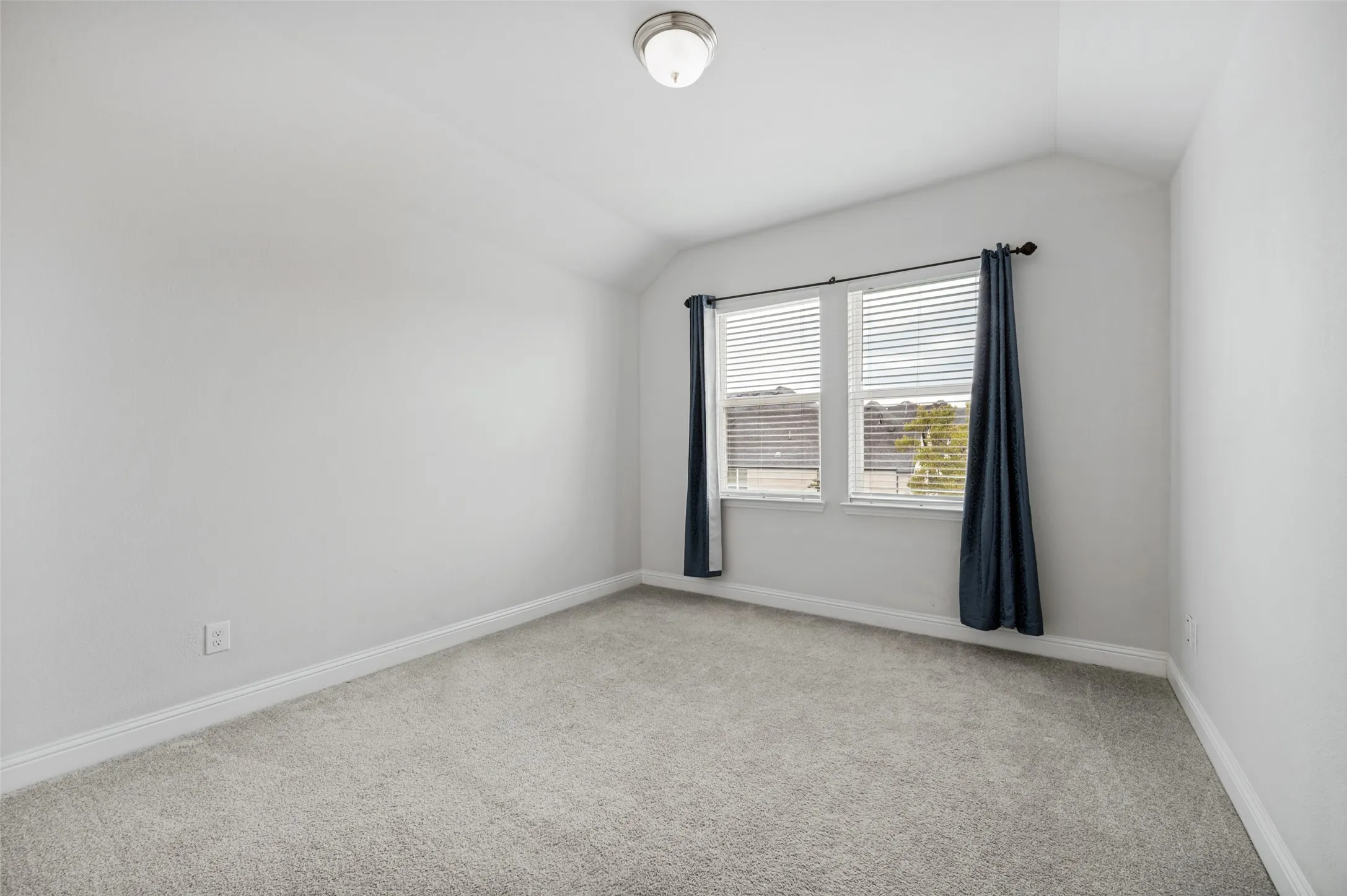 Upstairs bedroom with neutral paint palette, sloped ceilings, two windows, and light gray carpeting.