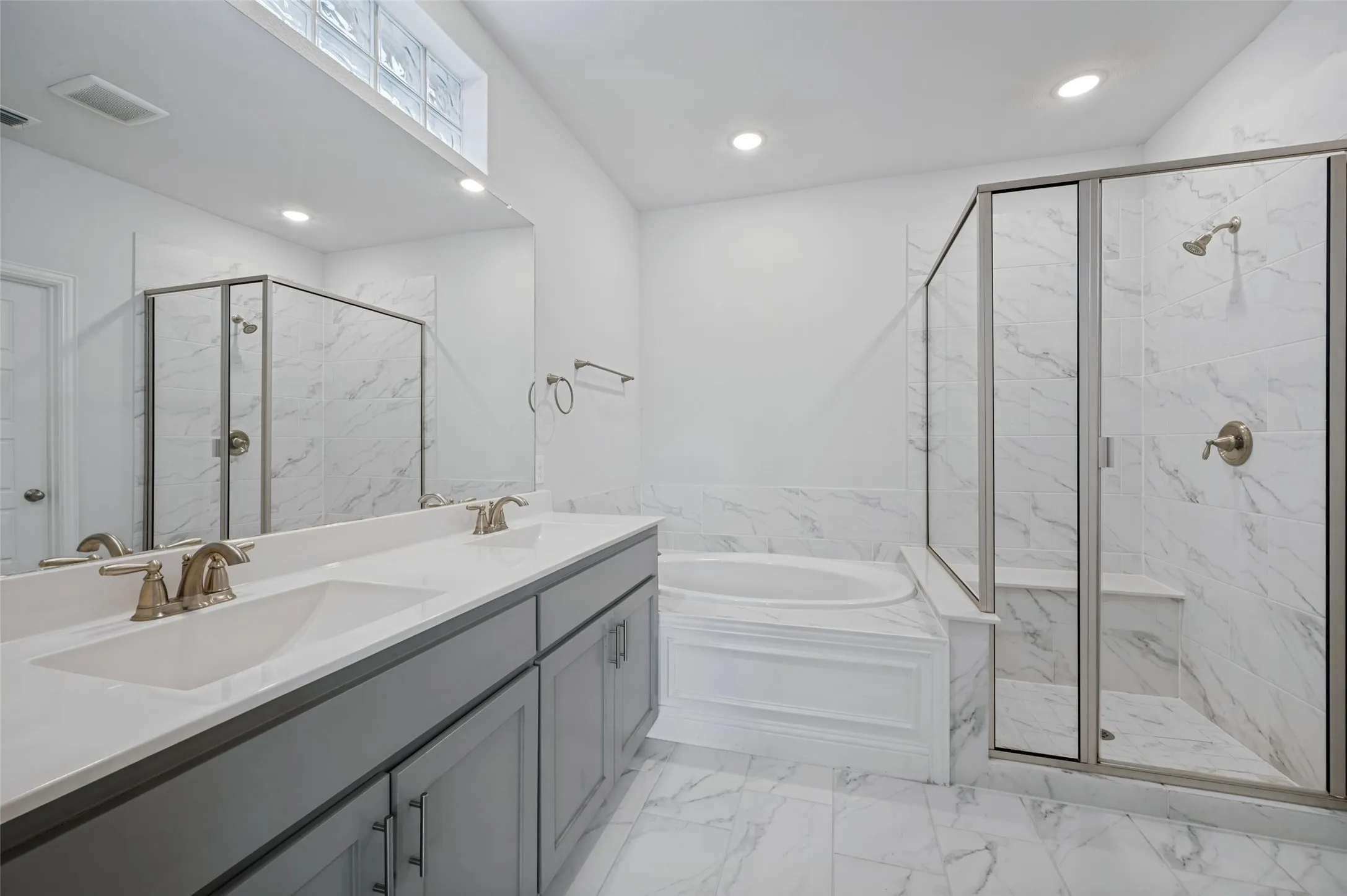 Oversized Primary Bath with dual vanity, gray cabinetry, quartz countertops, and brushed nickel fixtures. Huge walk-in closet.