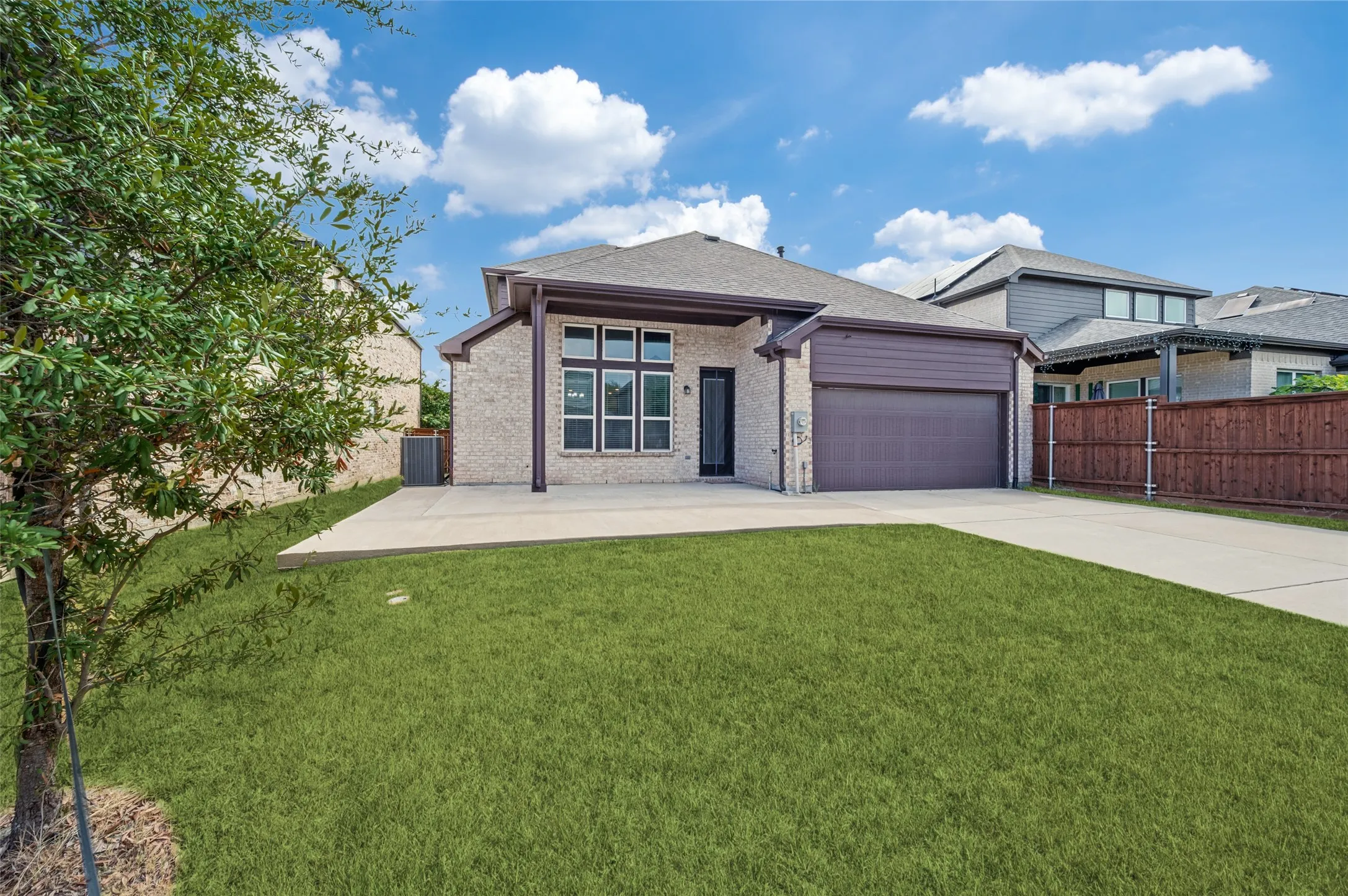 Brick exterior with dark trim accents, covered patio, extended pad, attached garage, and electric security gate.