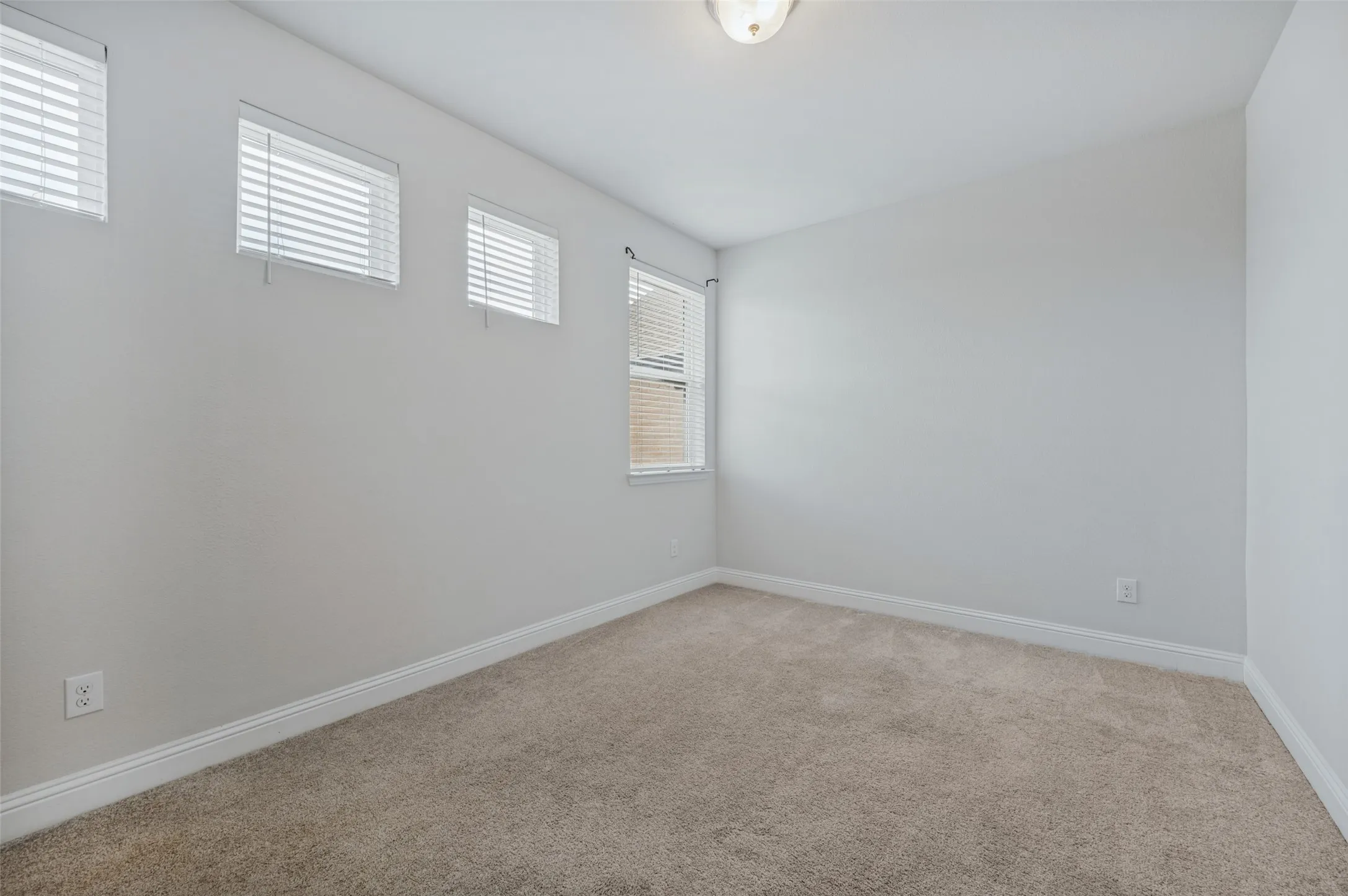 Additional upstairs bedroom featuring neutral wall color, carpet flooring, and multiple windows with blinds.