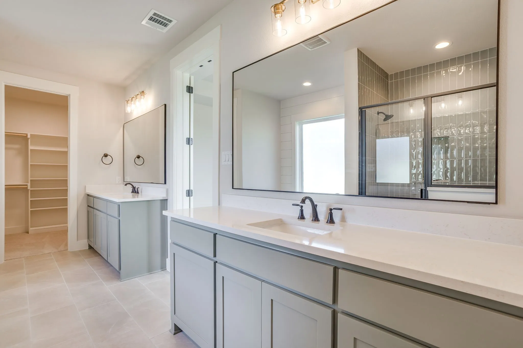 Dual vanity with individual sinks, white countertops, gray cabinetry, and matte black fixtures