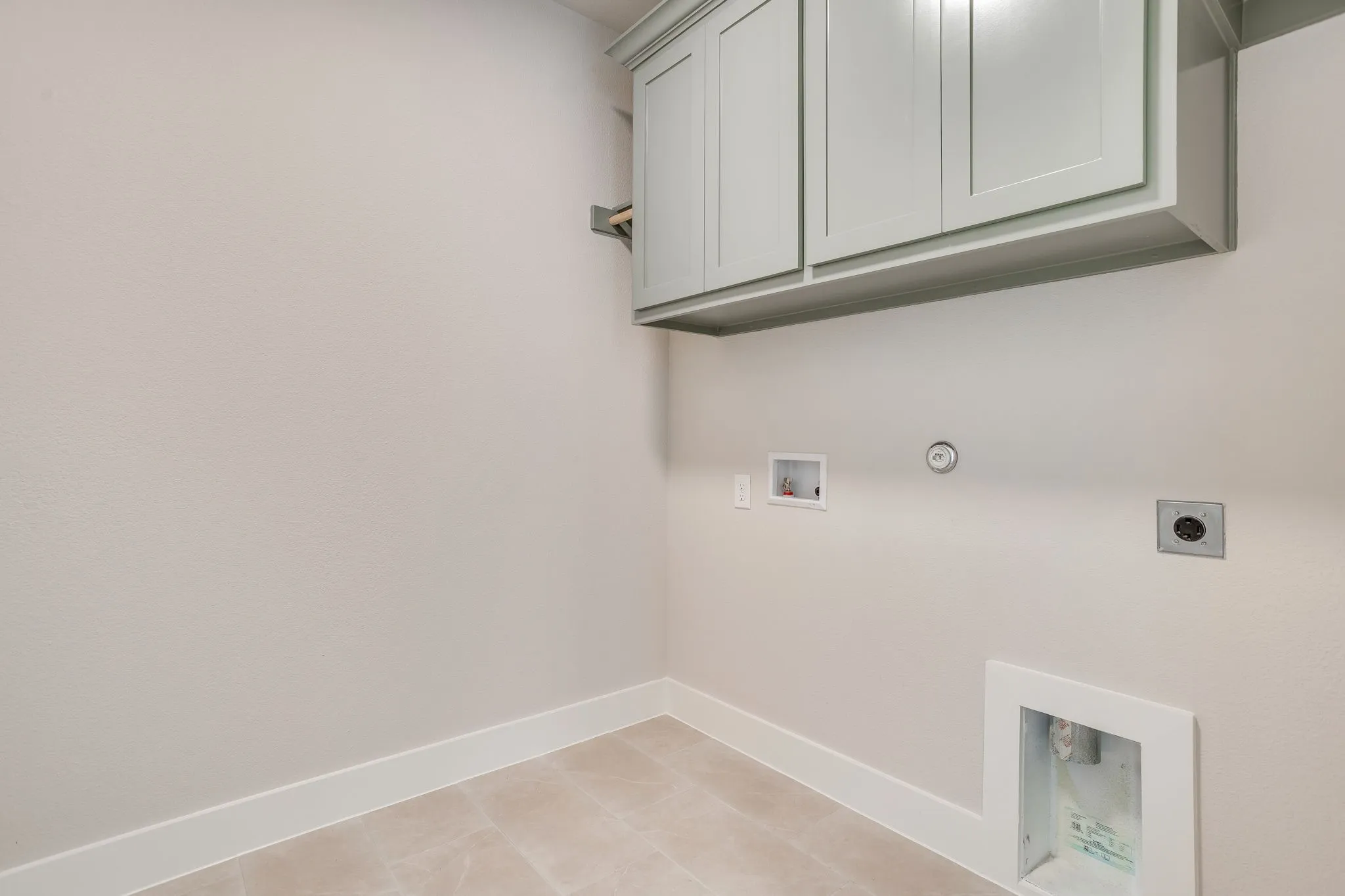 Light-colored upper cabinetry with shaker-style doors, light-toned walls, and square tile flooring