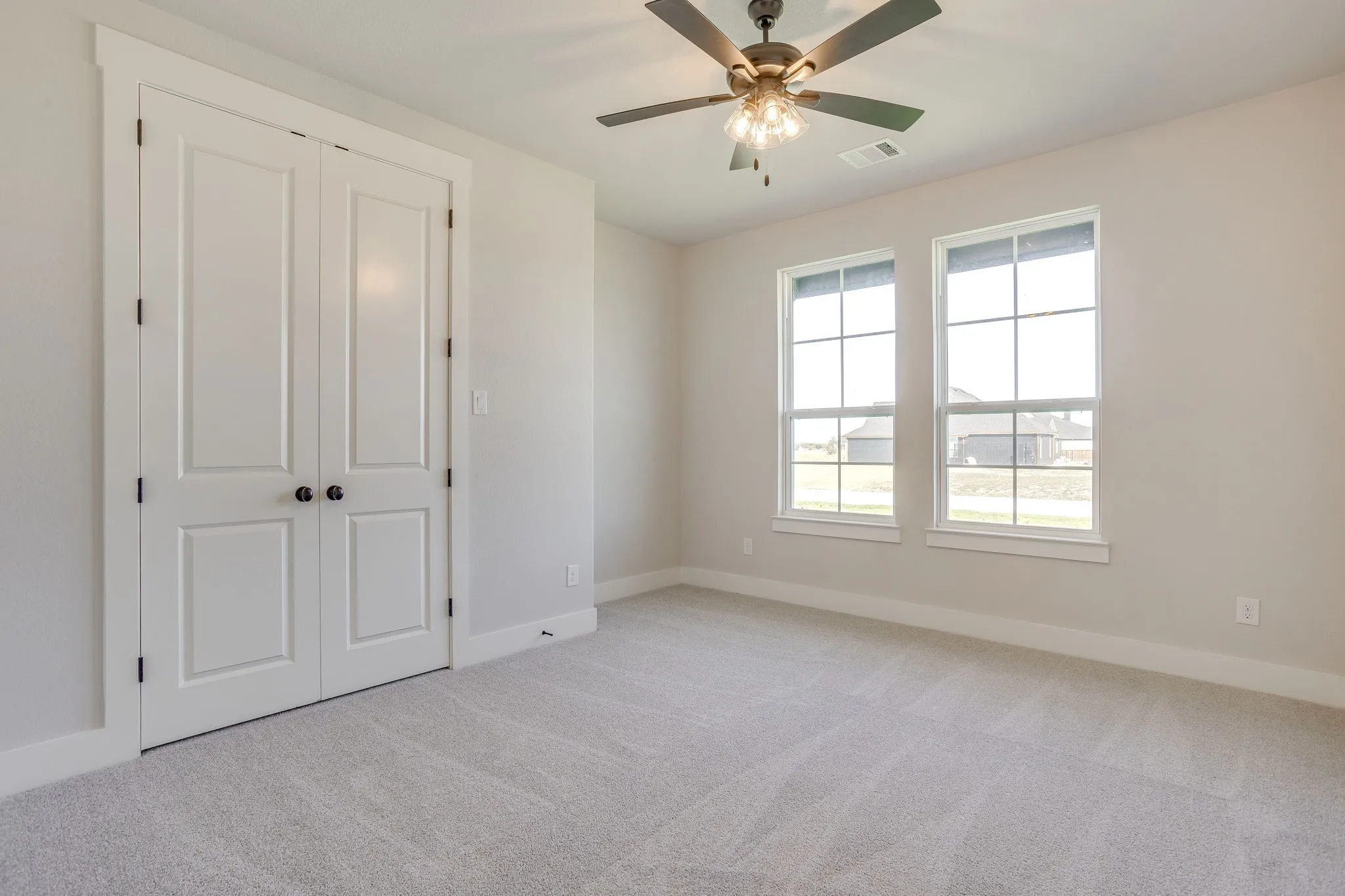 Dual pane windows, ceiling fan with integrated lighting, neutral wall color, white trim, and light-toned carpet