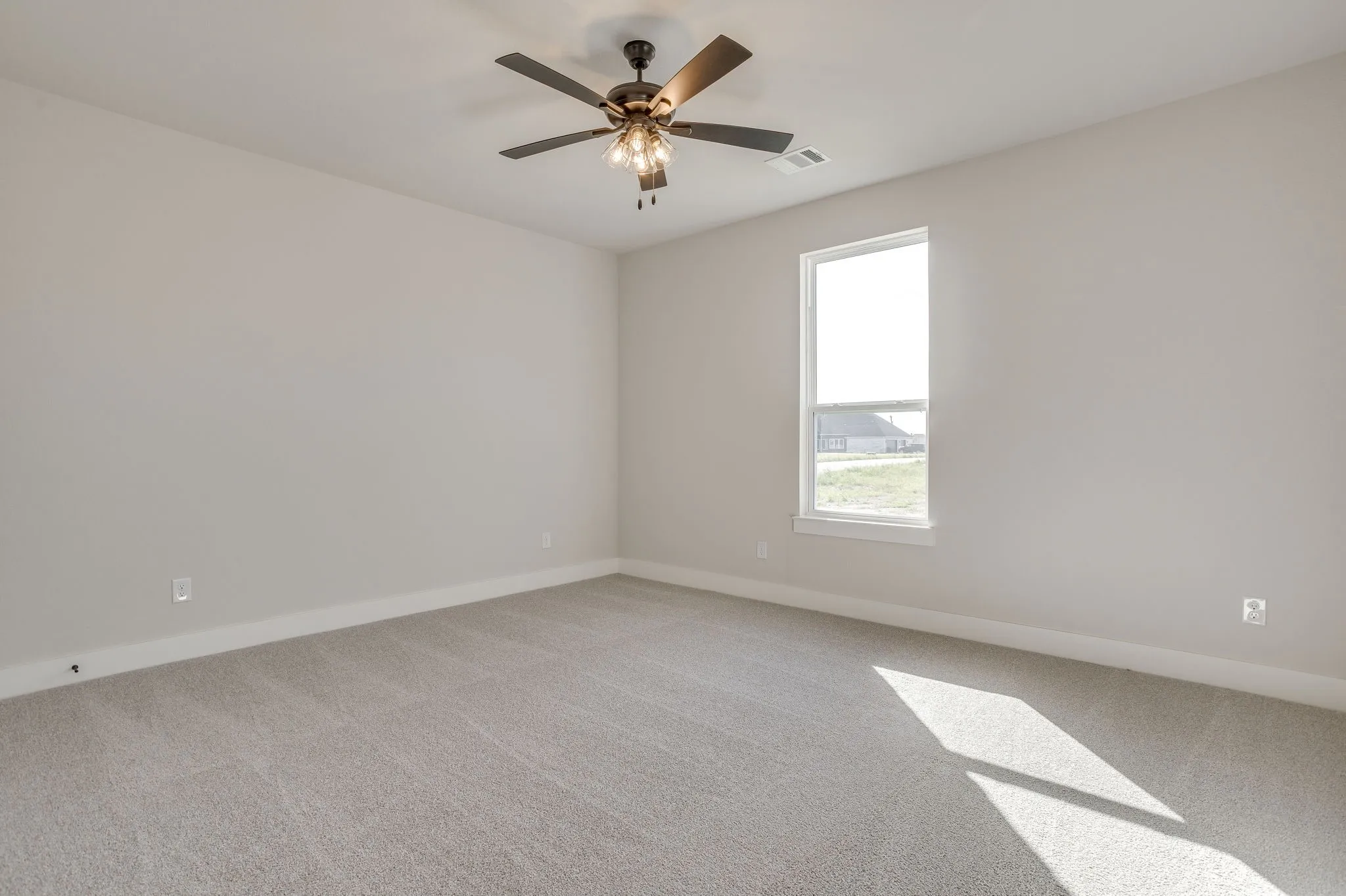 Neutral wall paint, ceiling fan with integrated lighting, window with white trim, and gray carpeting