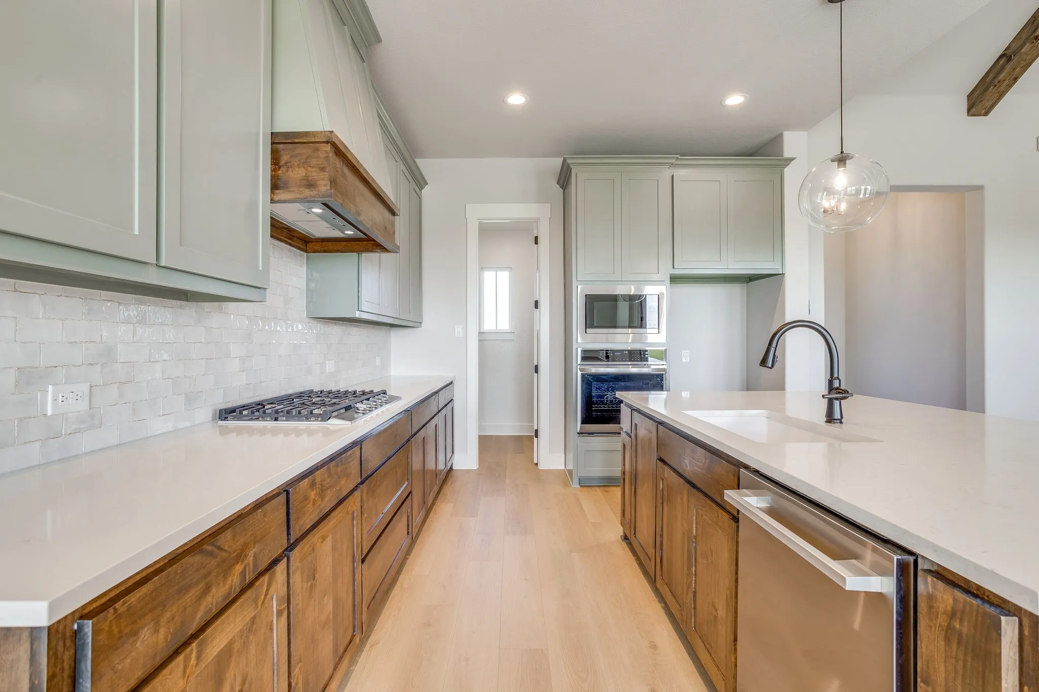 Kitchen featuring wood-finish lower cabinetry, light-toned upper cabinetry, stainless steel appliances, and a gas cooktop