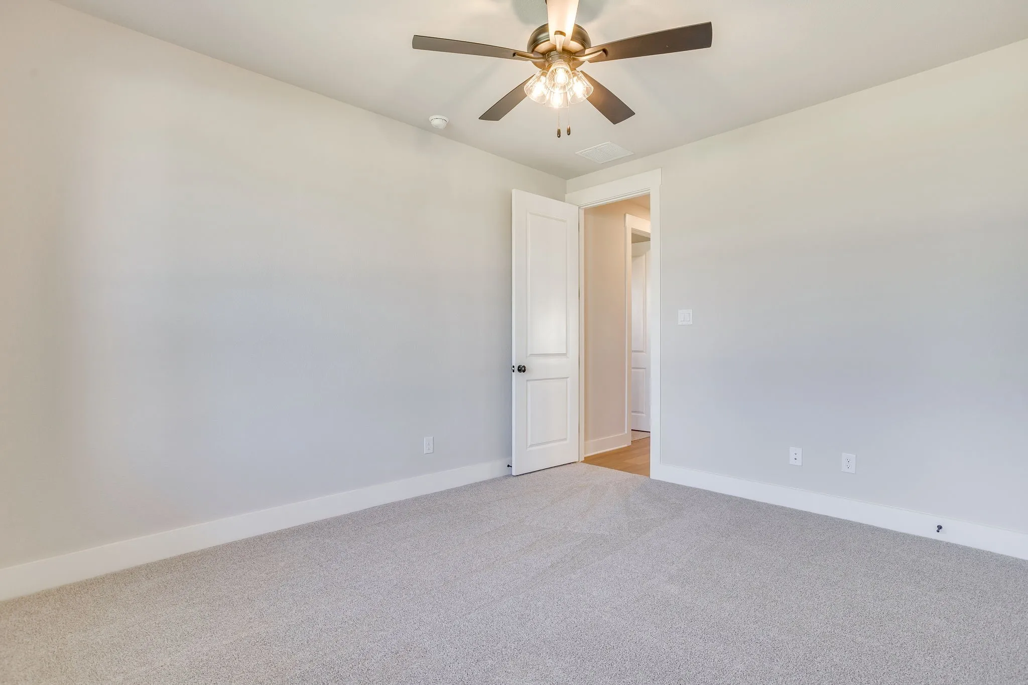 Neutral wall paint, ceiling fan with integrated lighting, carpeted flooring, white trim, and a paneled interior door