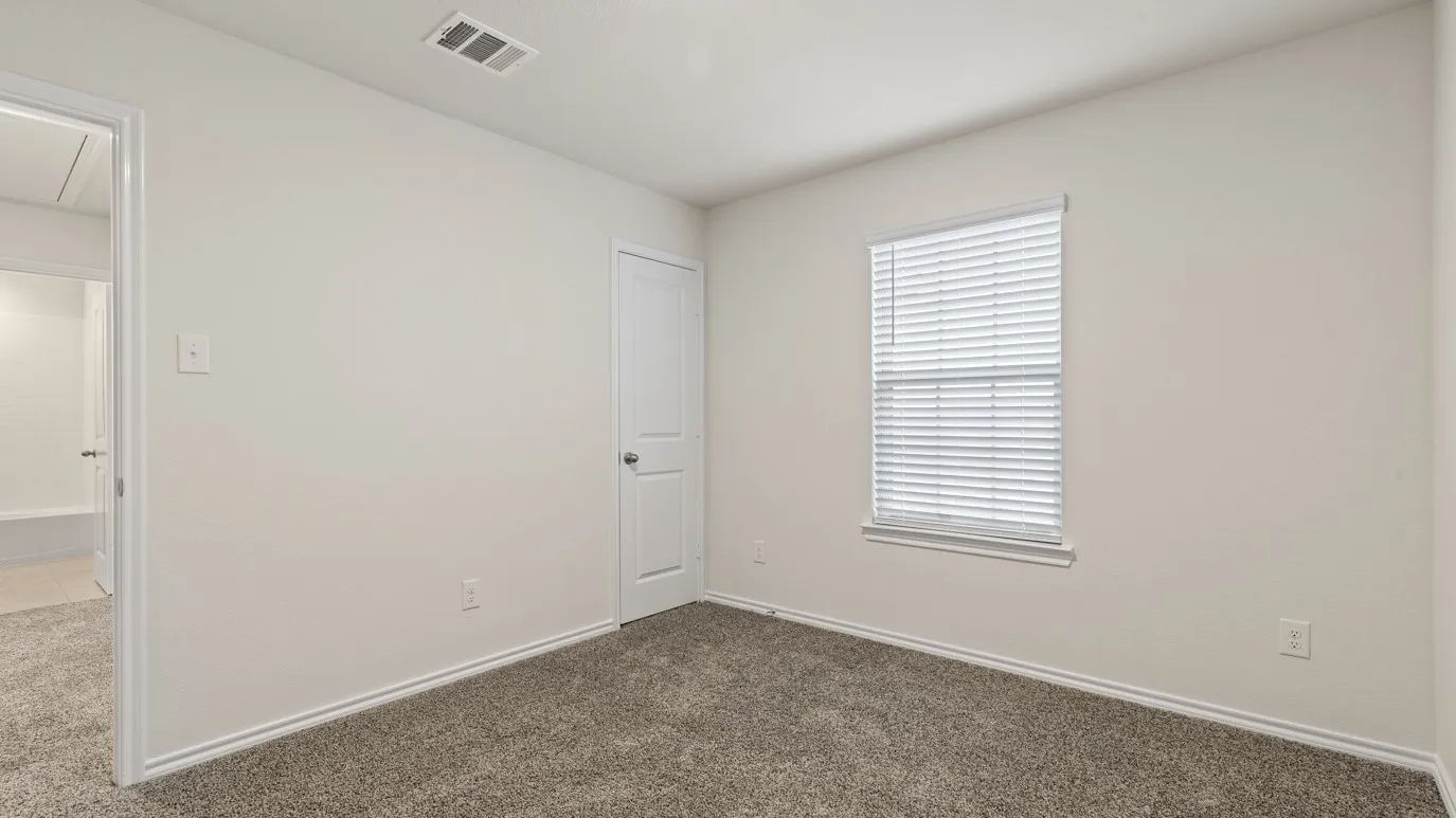 Neutral wall tones, window with horizontal blinds, textured carpeting, white trim, and a paneled door
