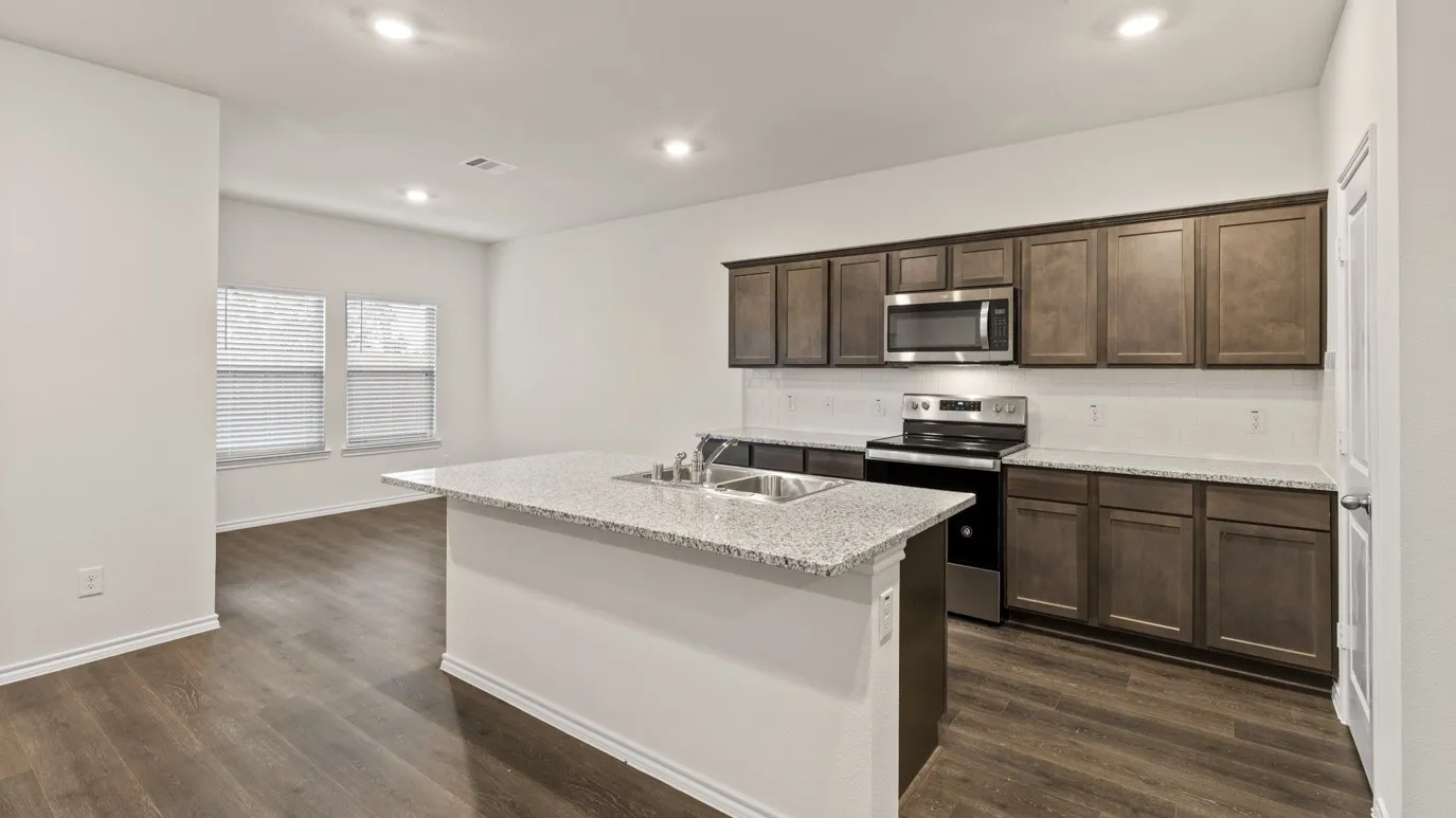 Kitchen featuring an island with a stainless steel sink, wood-finish flooring, recessed lighting, and dark wood cabinetry with stainless steel appliances