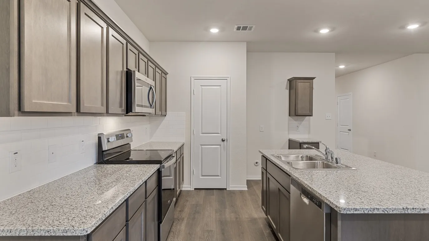 Kitchen featuring wood-finish cabinetry, stainless steel appliances, speckled countertops, a white subway tile backsplash, and recessed lighting