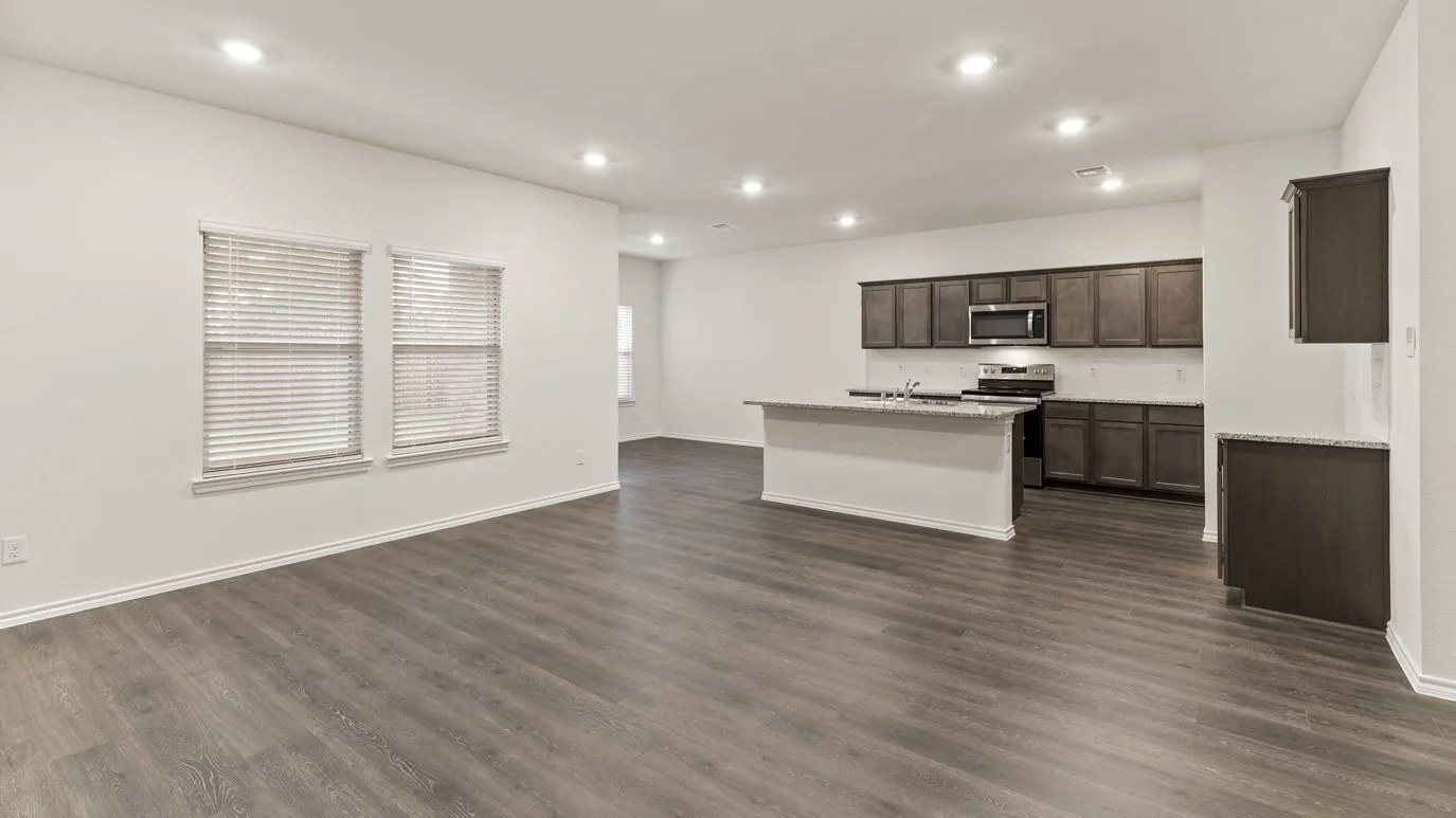 Open-concept living space featuring wood-finish flooring, recessed lighting, and a kitchen with dark cabinetry and a center island